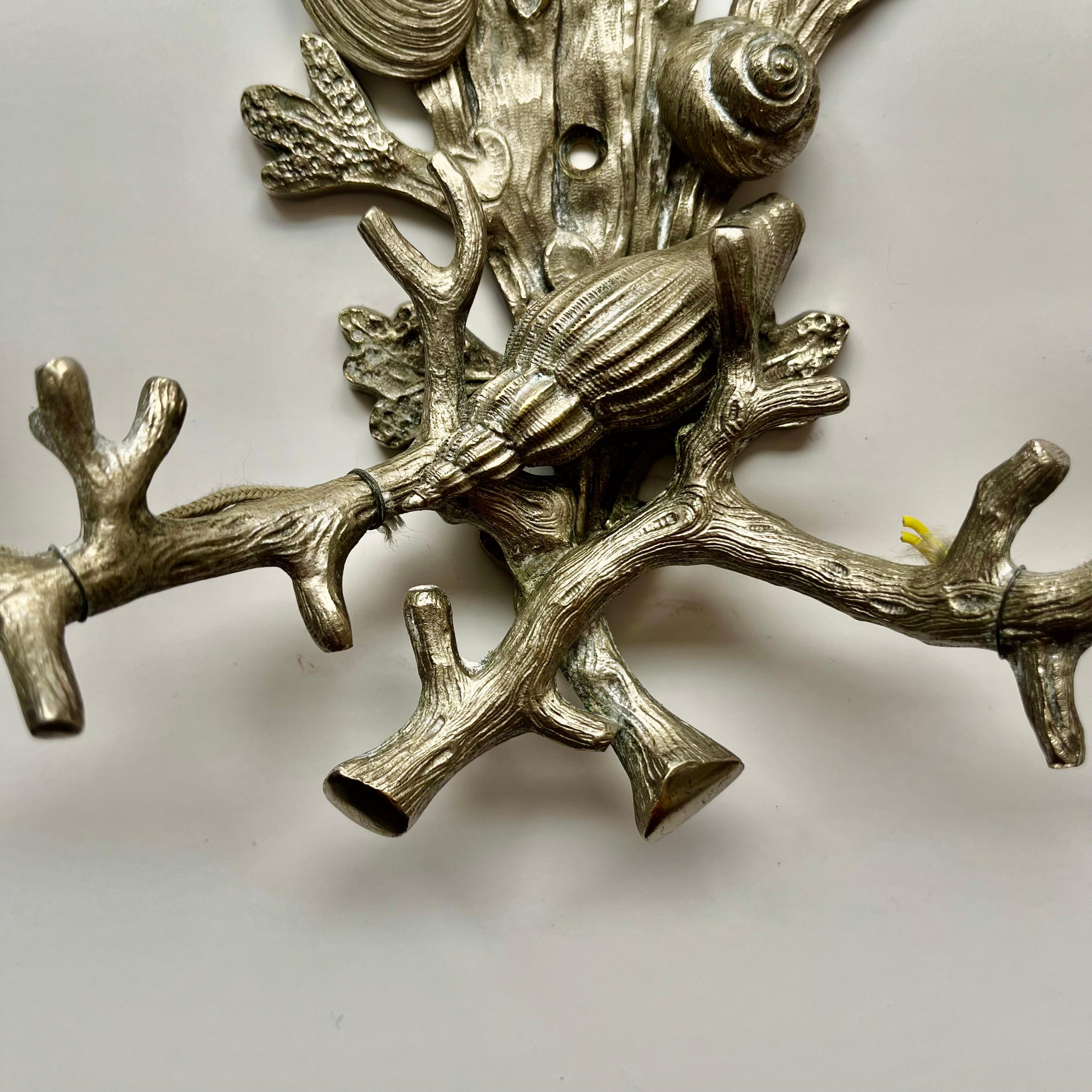 Un escultural aplique de pared de dos luces, fabricado en níquel plateado  y ricamente detallados con motivos marinos. 
Compuesta por algas y estrellas de mar, conchas y vieiras, la elegante ornamentación de esta pieza personifica la característica