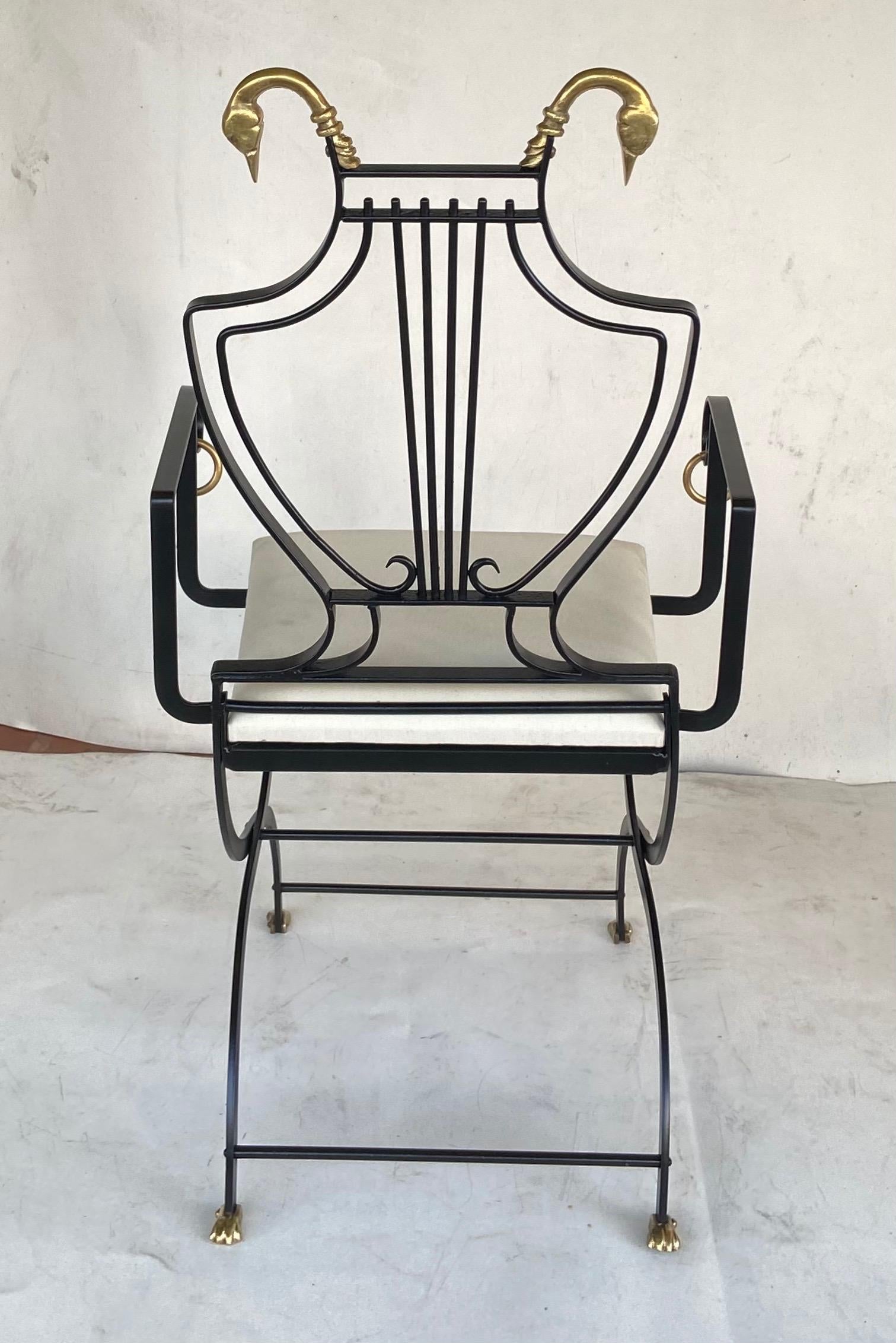 Inspired by Maison Jansen neoclassical wrought iron Lyre arm back chairs with brass swan heads at top round brass rings on arms and brass feet. From a Palm Beach estate meticulously restore. Priced individually.