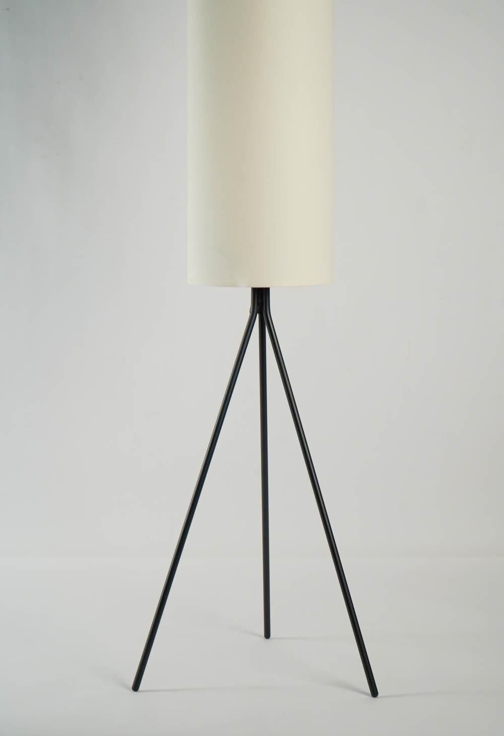 Tripod floor lamp made of black lacquered metal, handmade cylindrical shade of off-white cotton. A clever handle made of same material as the feet, curve shaped.
1 bulb.

Lampadaire Maison Lunel, 1950 
Piétement tripode en fer forgé noir se