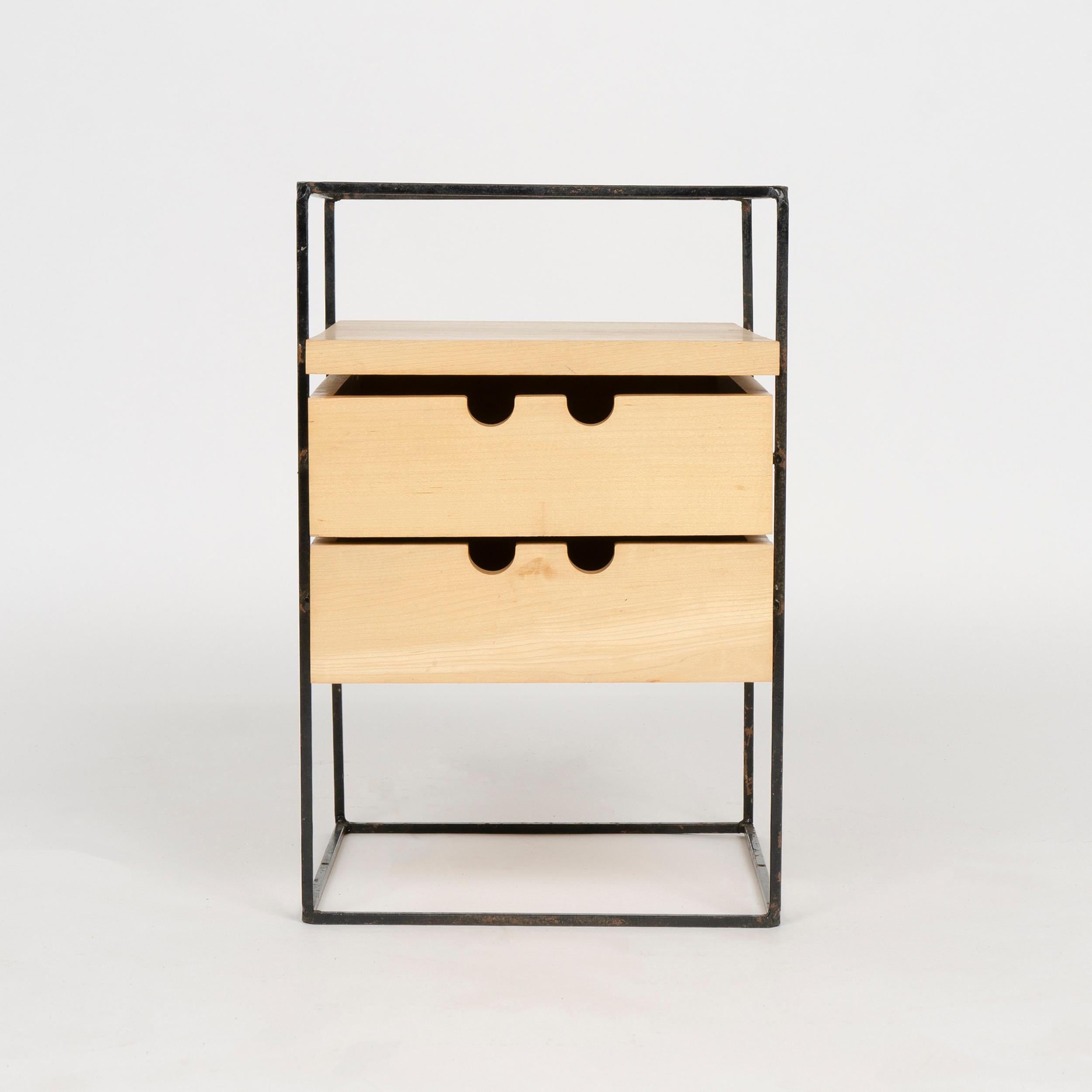 A small table top maple storage unit with two drawers supported by a black steel frame base. This desk organizer is a product from the Planner Group, a coordinated contemporary furniture group, designed by Paul McCobb and made in the USA.