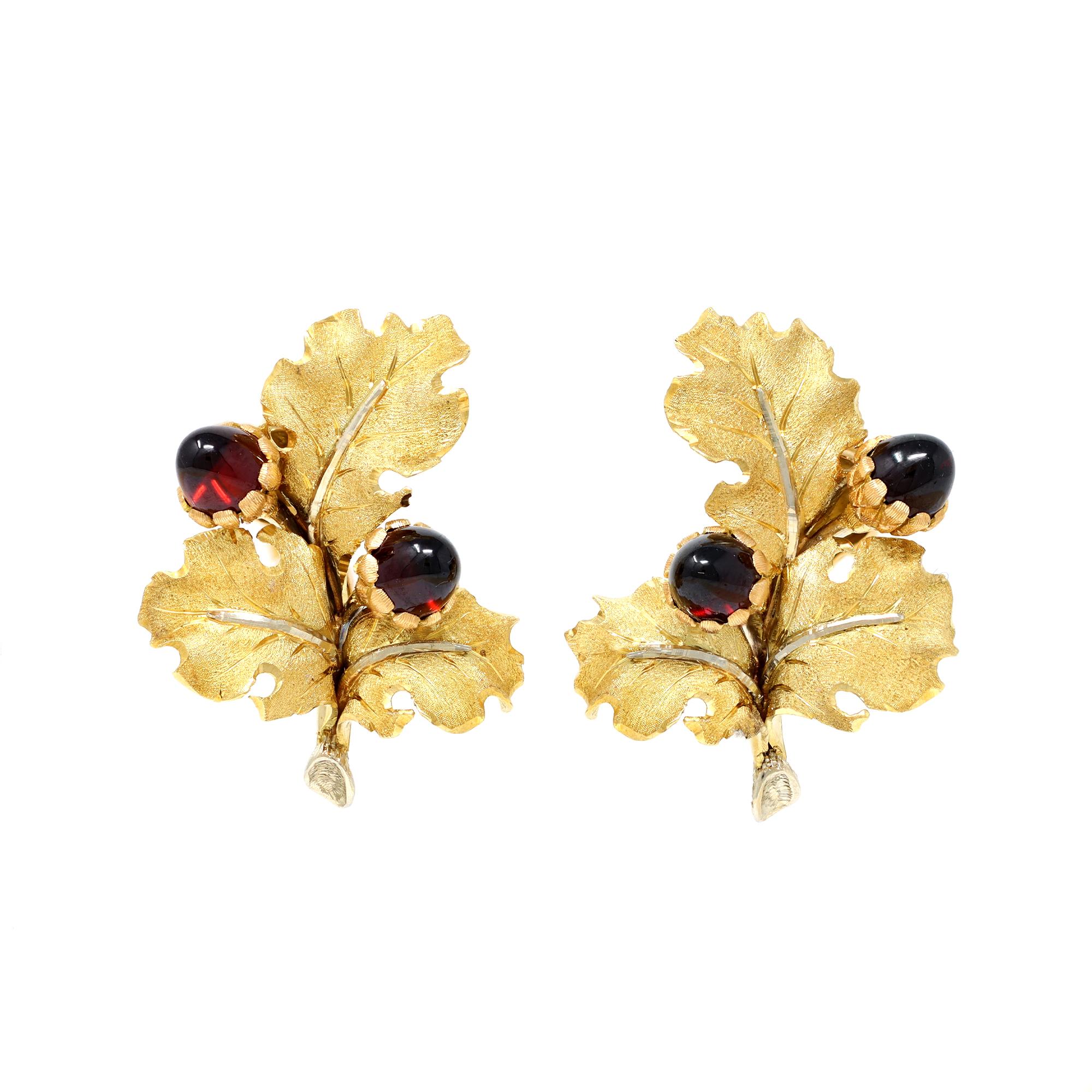 A fantastic set including a brooch and clip-on earrings by Mario Buccellati, Italy, c.1950, the brooch designed as a series of textured gold leaves set with cabochon garnet acorns, gross weight 18.1 grams, measuring 2 ⅛ by 1 ½ inches; the clip-on of