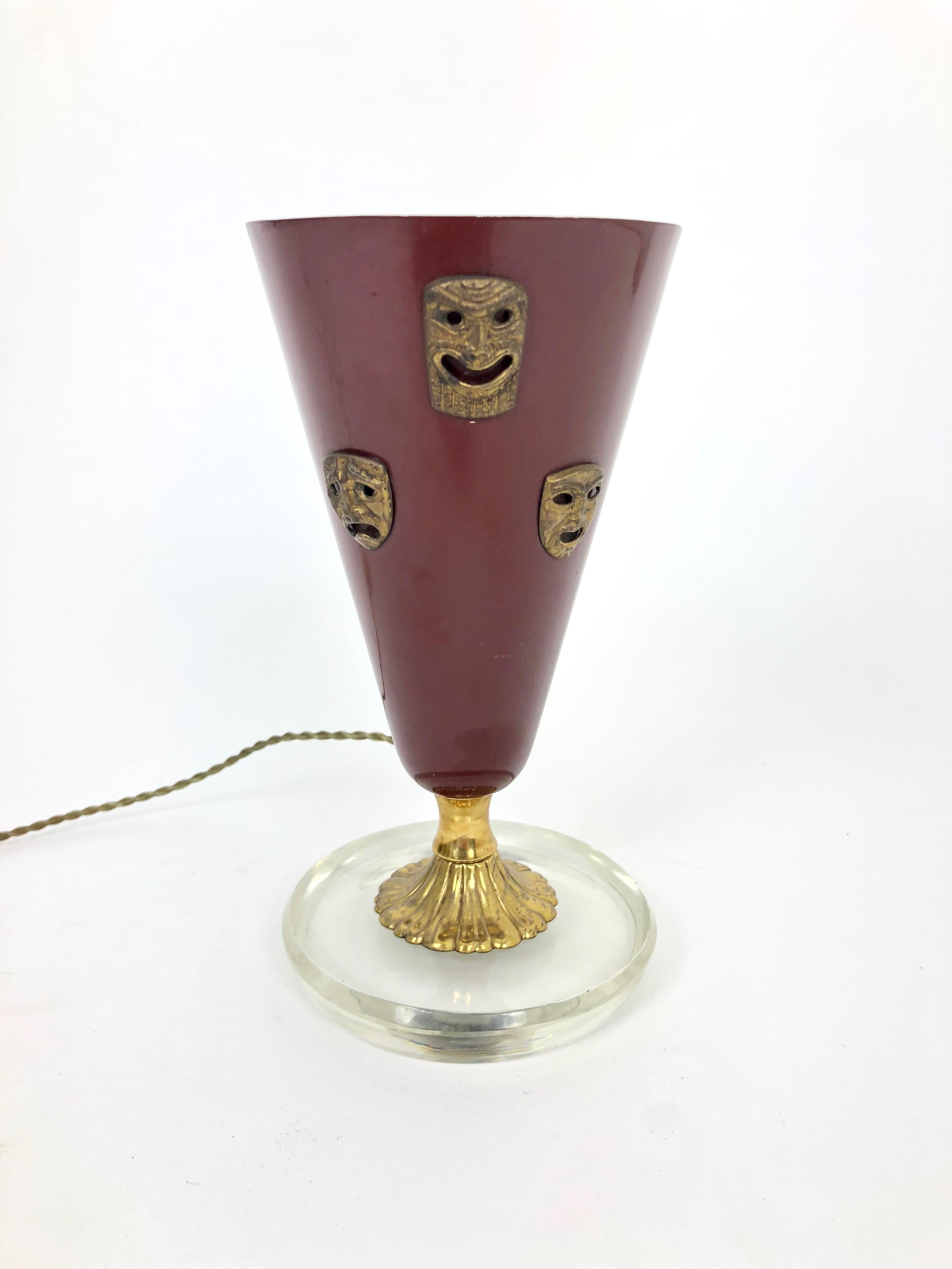 This table lamp represents the Comedy and Tragedy masks, made of brass on a surface of steel, and stands on a massive glass plate.
The item's style recalls the one of Gio Ponti.