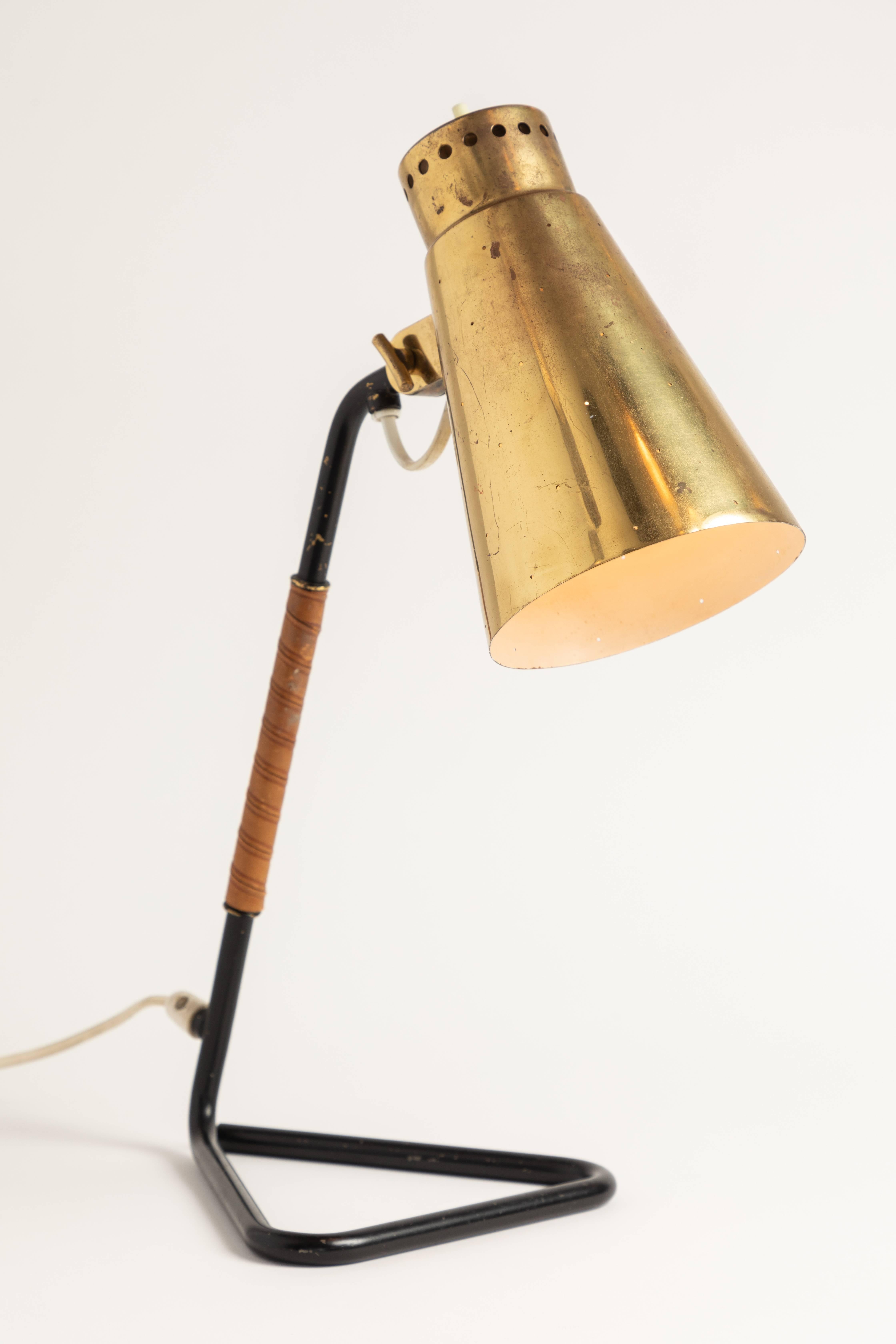 1950s Mauri Almari brass and metal table lamp for Itsu. A rare and elegant table lamp executed in brass, black painted metal and wrapped leather. A contemporary of Paavo Tynell, the refined work of Mauri Almari has made him an increasingly valued