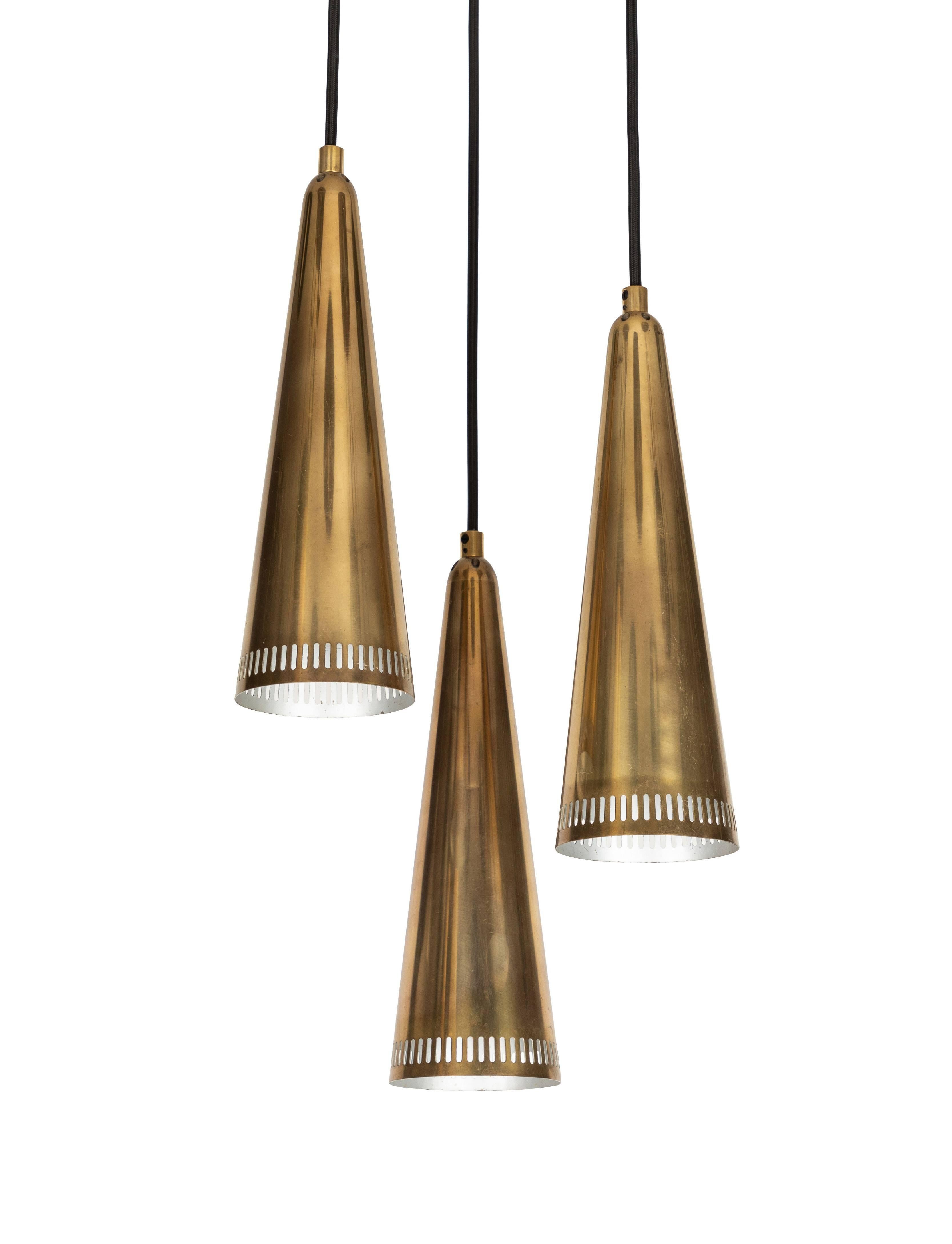 1950s Mauri Almari 'K2-48' chandelier for Idman. This cascading chandelier features a trio of perforated brass cones that each measure 13 inches H x 4.25 inches W.