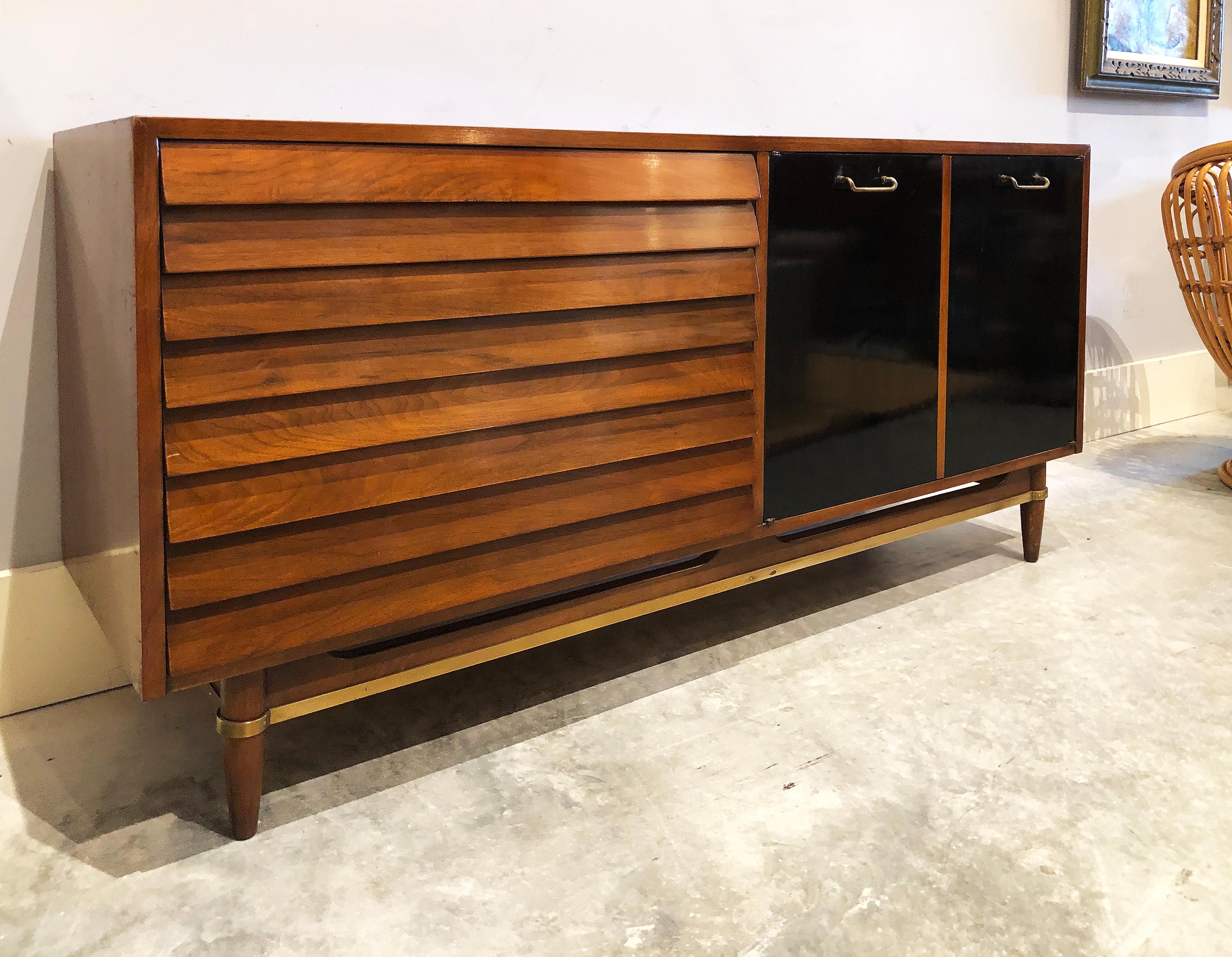 1950s Merton Gershun American of Martinsville credenza cabinet

Offered for sale is a 1950s stunning credenza/cabinet/dresser by Merton Gershun for American of Martinsville. Behind two doors with black laminate are drawers and open shelves. To the