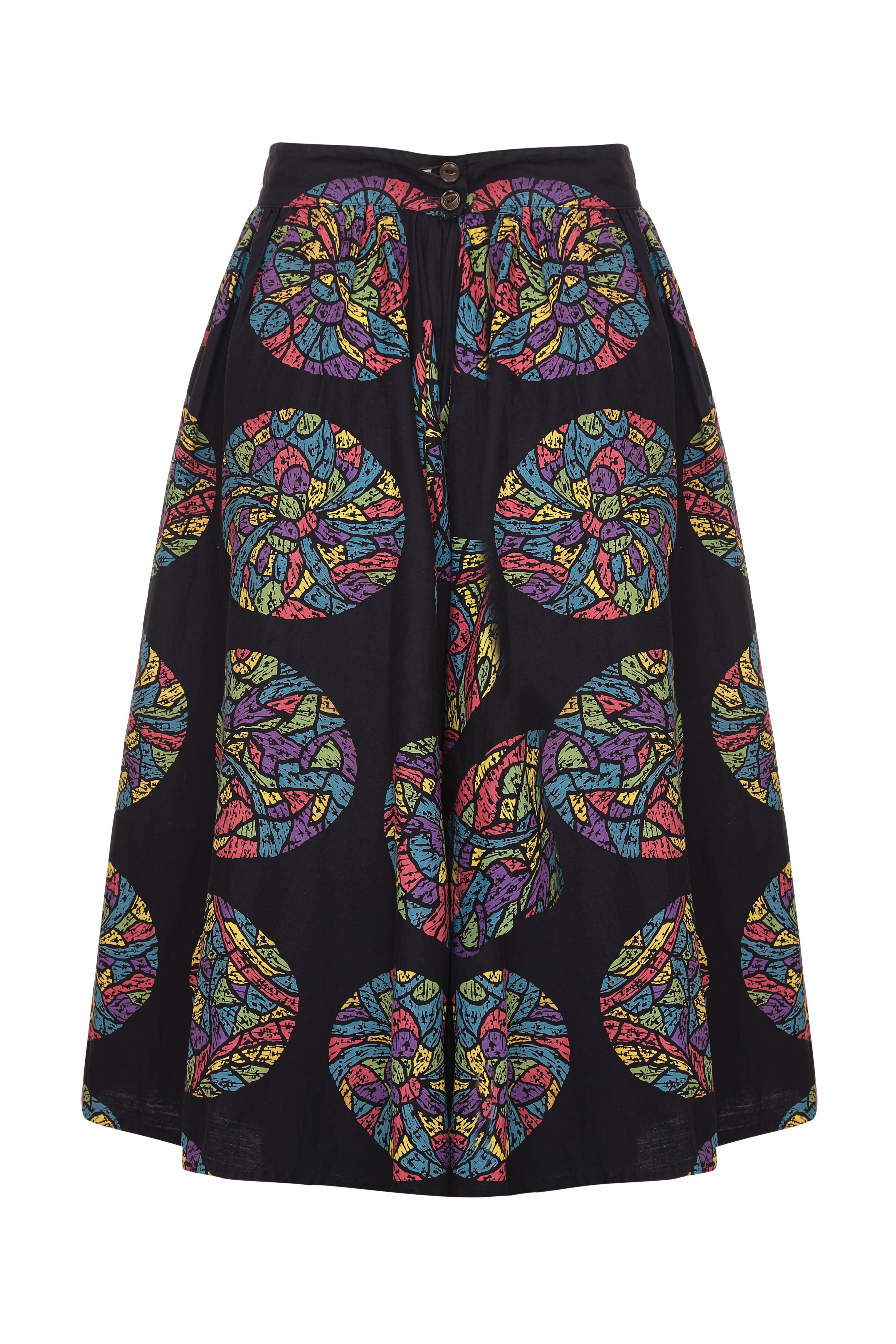 This charming original 1950s Mexican black cotton festival skirt with a vibrant circular multicoloured print in green, blue, fuchsia, and yellow tones is in superb vintage condition and is a wonderfully versatile piece. It features a deep forward