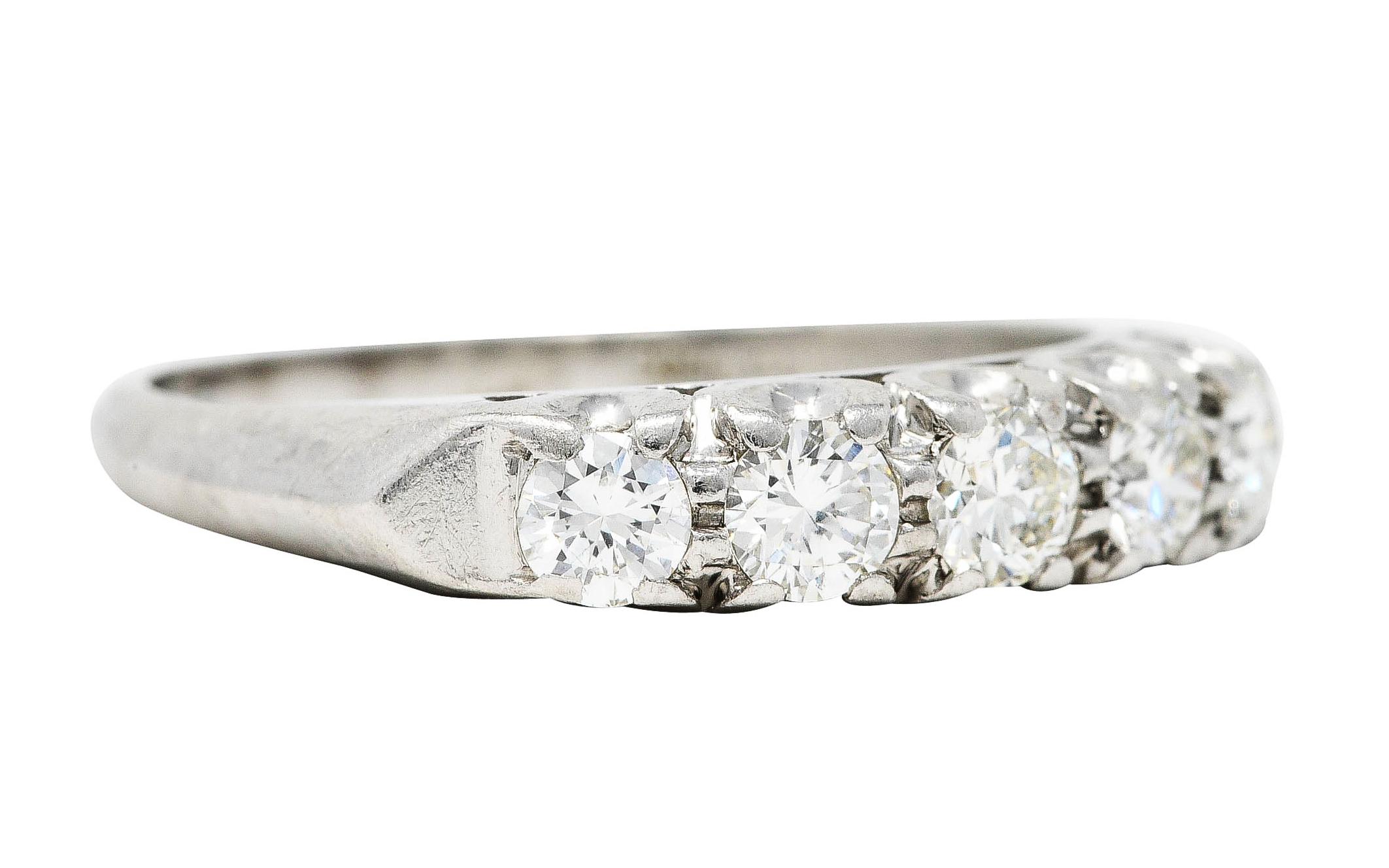 Band ring centers five prong set round brilliant cut diamonds

Weighing approximately 0.50 carat - G/H in color with VS clarity

Accented by angular knife's edge shoulders

With pierced fishtail profile

Stamped for platinum

Circa: 1950's

Ring
