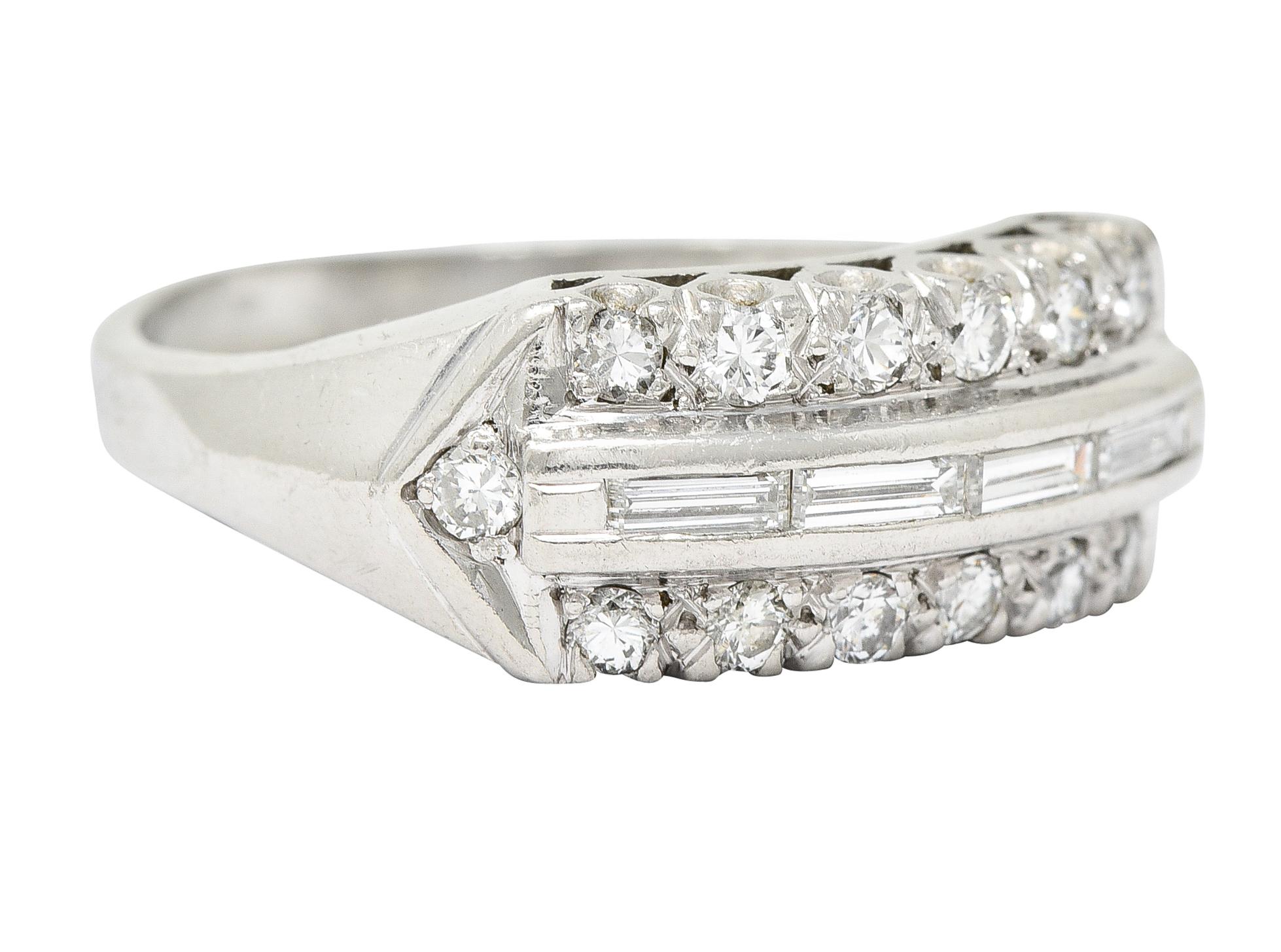 Band ring is comprised of three rows of diamonds. With a raised central channel of straight baguette cut diamonds. Flanked North and South by round brilliant cut diamonds set in a fishtail motif. Total diamond weight is approximately 0.50 carat with