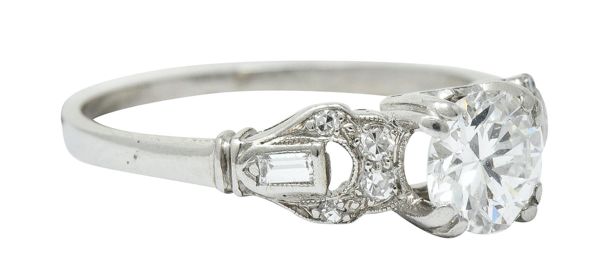 Centering a transitional cut diamond weighing approximately 0.64 carat; F/G color with VS clarity

Set in a stylized basket setting with doubled prongs and flanked by buckle motif shoulders

Shoulders are accented by baguette and single cut diamonds