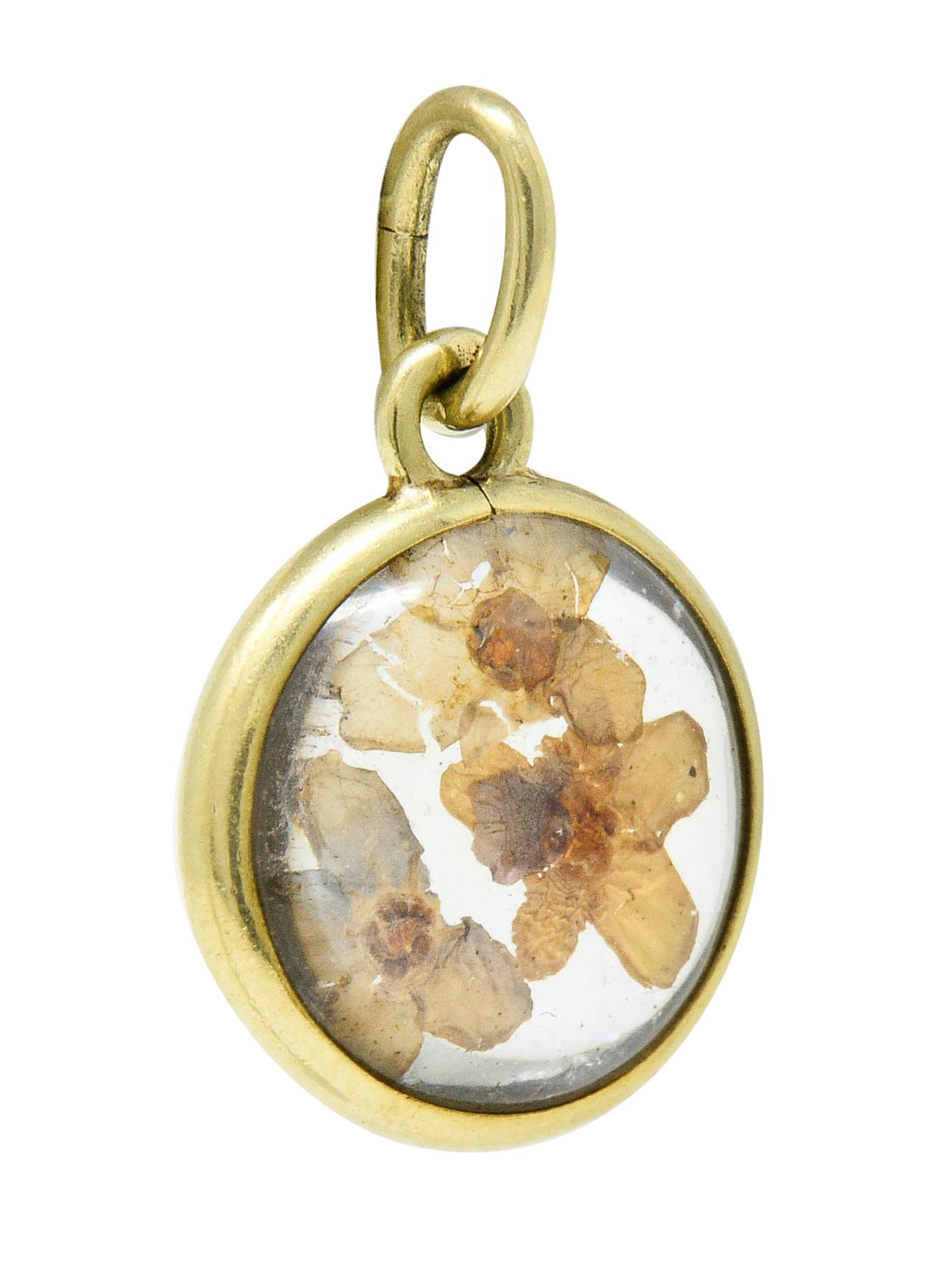 Circular charm is designed as pressed flowers encased in resin

Completed by a polished gold surround and jump ring bale

Tested as 14 karat gold

Circa: 1950s

Measures: 1/2 x 3/4 inch (including bale)

Total weight: 1.7 grams

Dreamy. Floral.