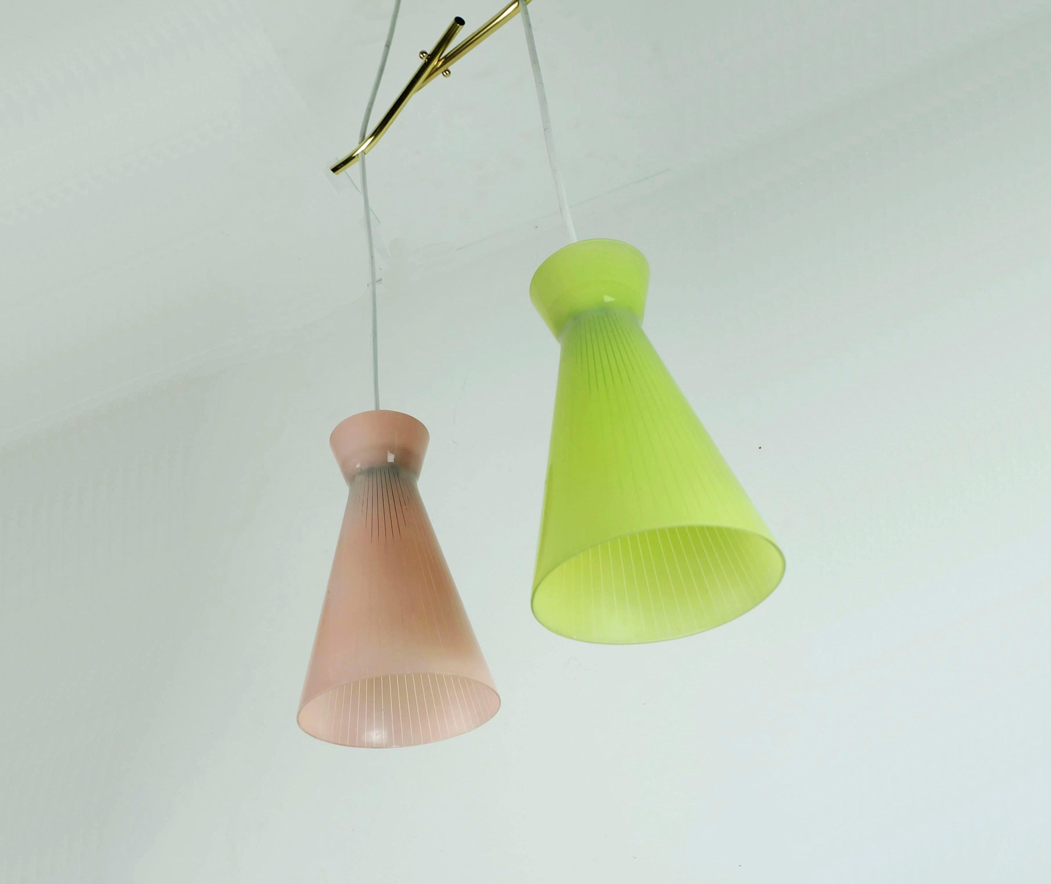 Bellissima lampada a sospensione degli anni '50 con due paralumi in vetro, uno rosa e uno verde lime, con un motivo a righe sottili. Dettagli in ottone, filo elettrico bianco. Contiene 2 lampadine E14.
 
Dimensioni: Lunghezza 80 cm, larghezza 31 cm,