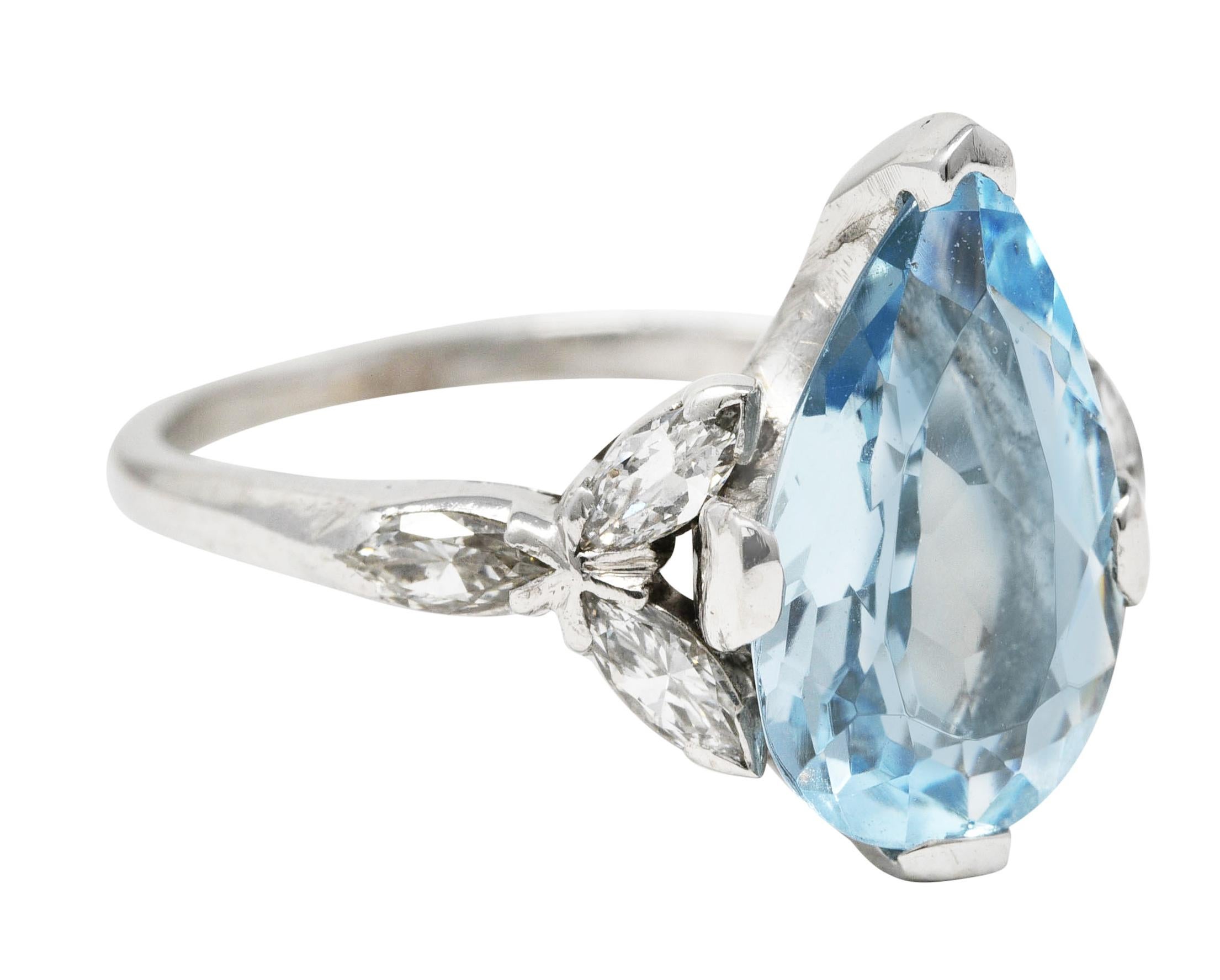 Featuring a pear cut aquamarine weighing approximately 1.65 carats. Eye clean with medium light greenish blue color. Set by wide prongs and flanked by stylized cluster shoulders. Comprised of triads of V prong set marquise cut diamonds. Weighing