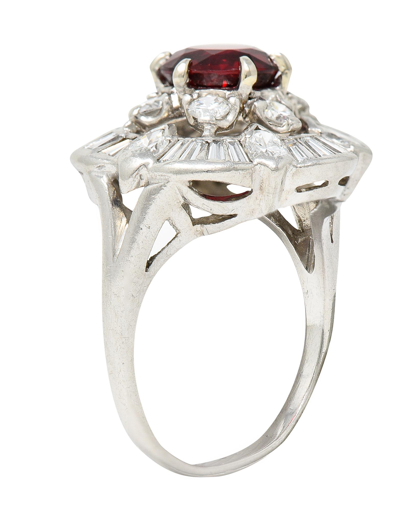Centering a round cut spinel weighing 1.52 carats - natural and vividly red in color. Surrounded by a double halo of diamonds. Inner halo is a floral cluster comprised of round brilliant cut diamonds. Outer halo is comprised of flush set baguette