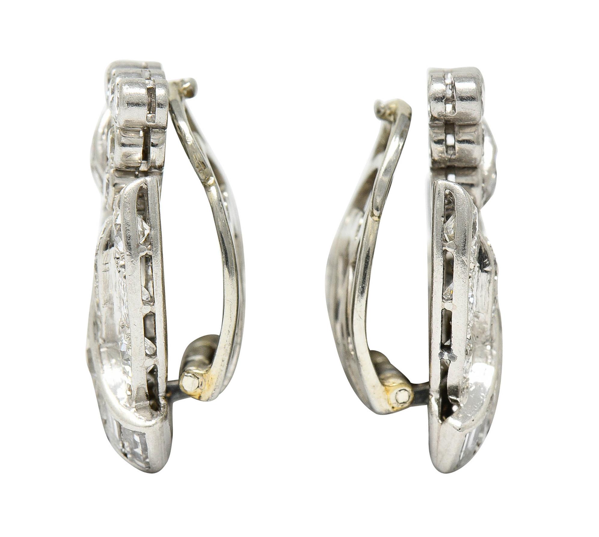 Ear-clips are designed as a ribboned swirl with bezel set accents

Featuring baguette, square step, and old European cut diamonds

Weighing in total approximately 3.07 carats with G to J color and overall SI clarity

Completed by white gold hinged
