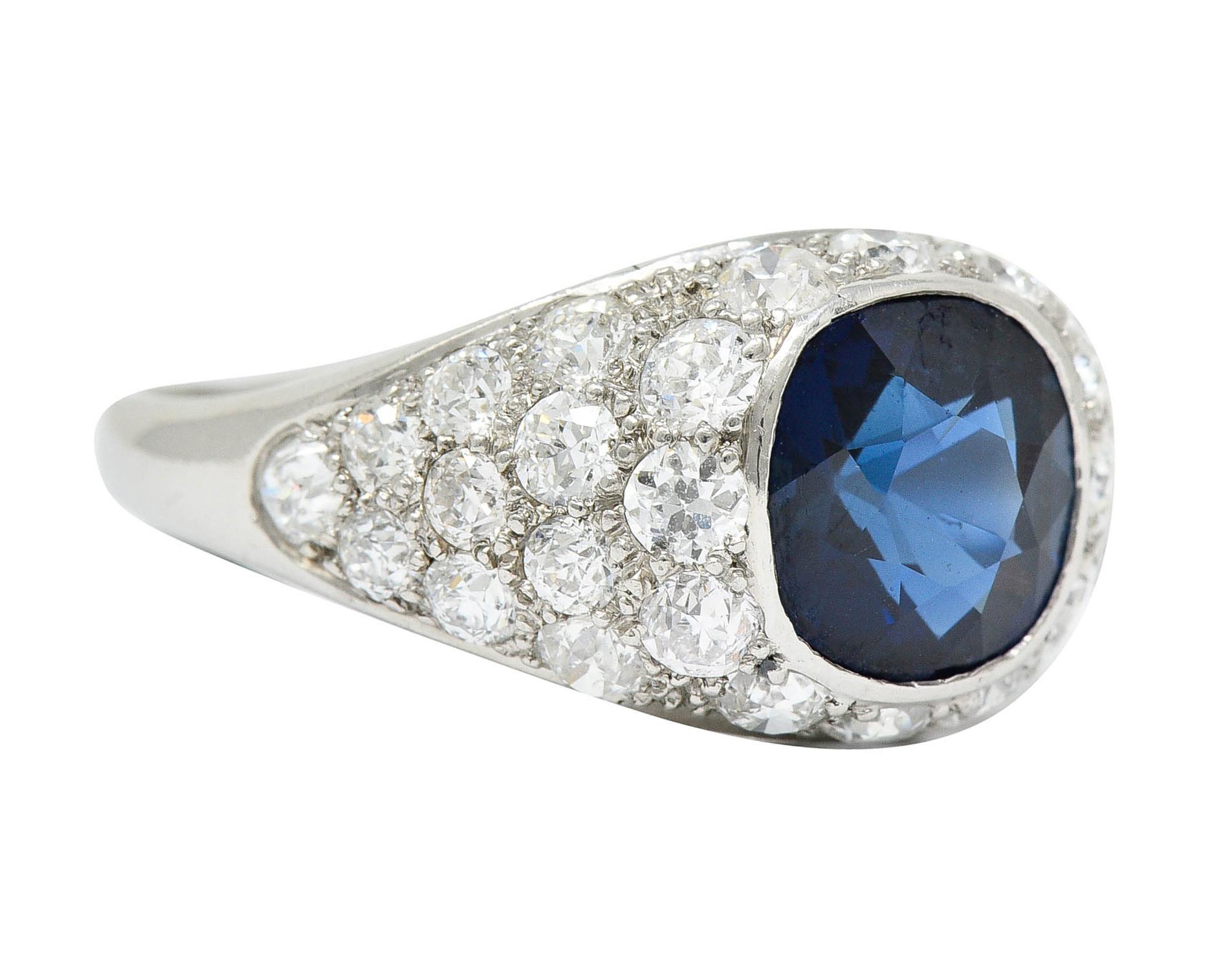 Centering a bezel set cushion cut sapphire weighing approximately 2.84 carats

Transparent medium-dark blue with no indications of heat and Cambodian in origin
Surrounded by pavè set old European and transitional cut diamonds

Weighing in total