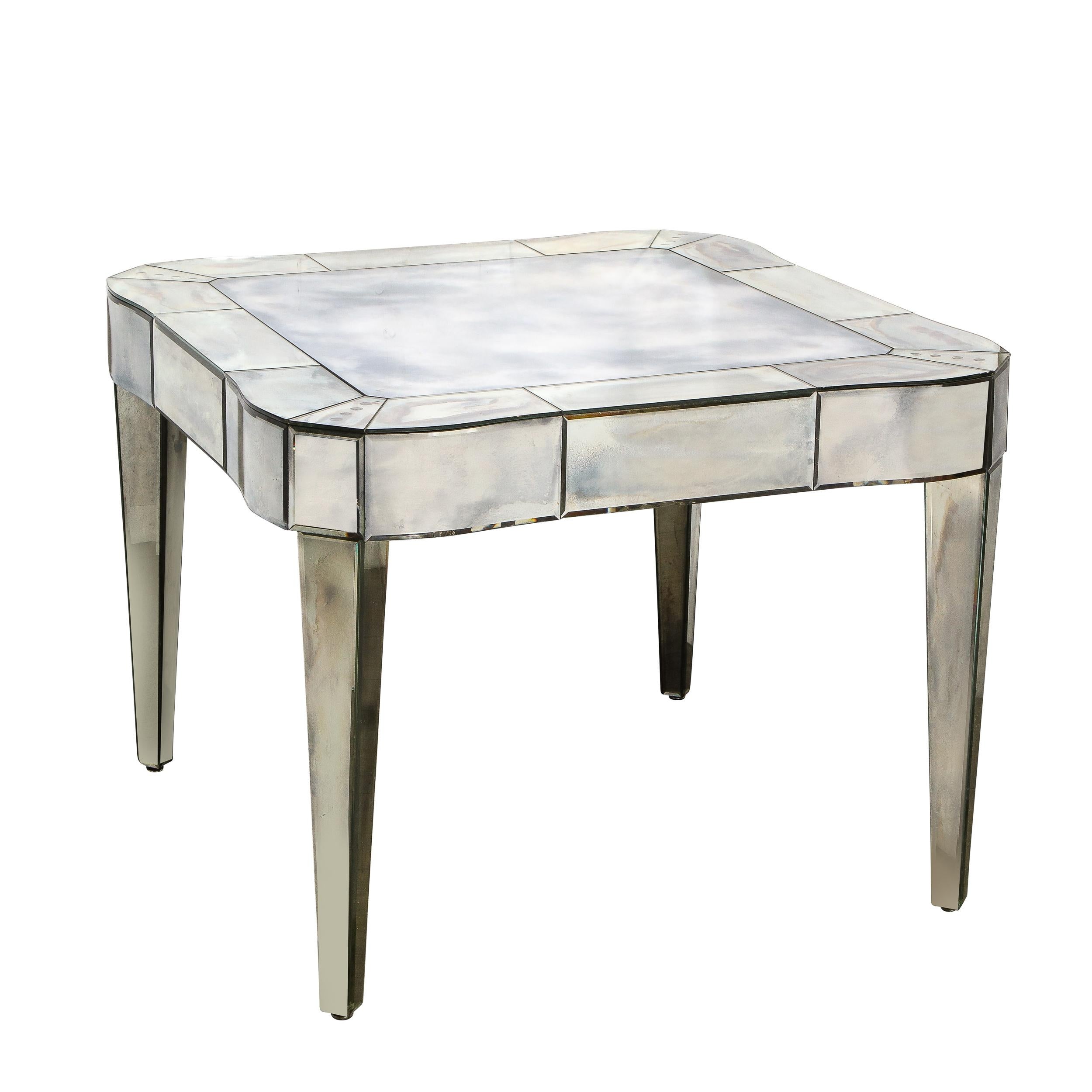 This stunningly beautiful mid-century smoked mirrored table with slightly bowed and curved corners was realized in America. This timeless piece features a beveled, tessellated top with a undulating mirrored apron that connects to tapered elegant