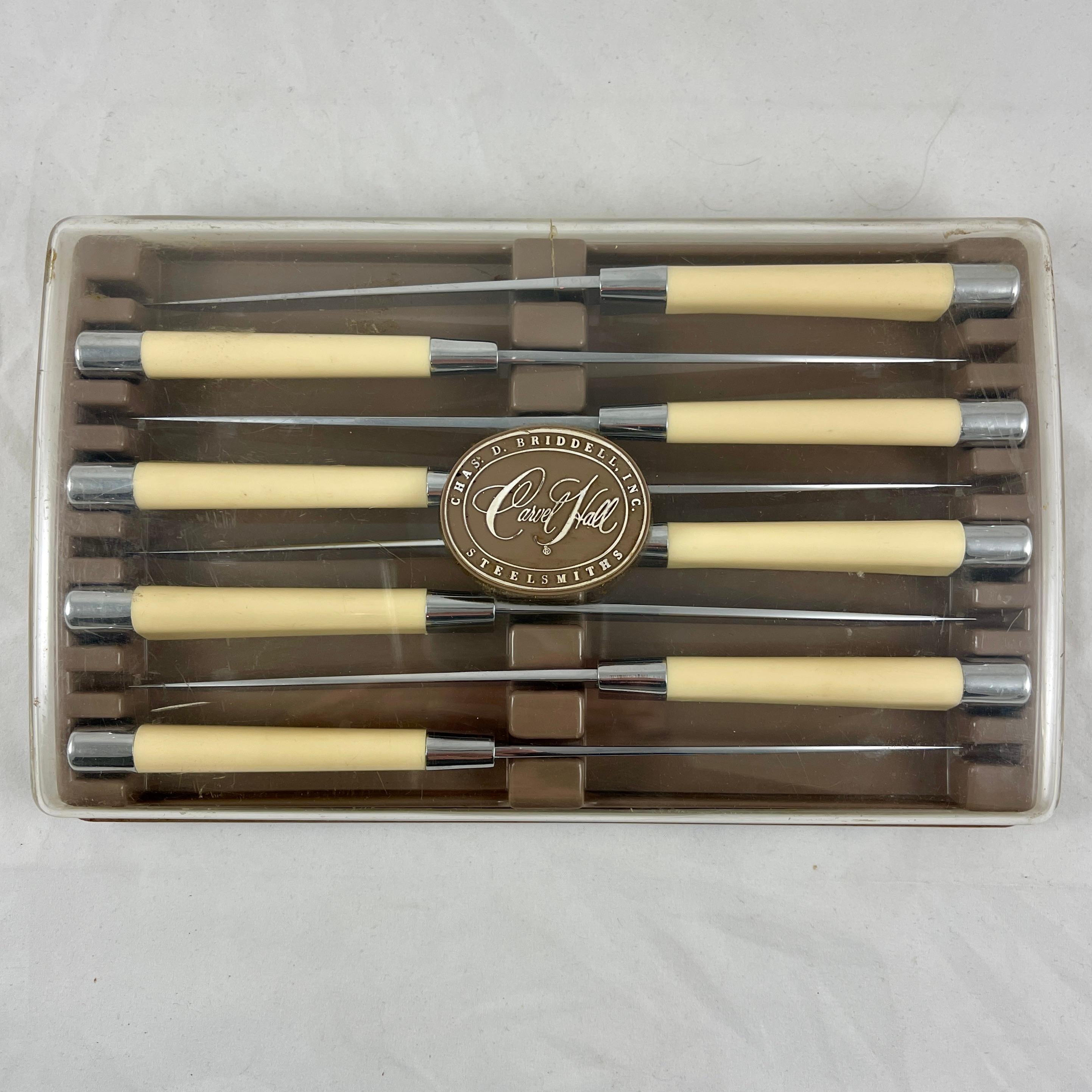 A set of eight Carvel Hall steak knives by Chas. D. Briddell, Inc. circa 1950s.

Stainless steel blades and end caps are fitted with ivory colored plastic handles resembling Bakelite.
Great Mid-Century styling in the original plastic storage