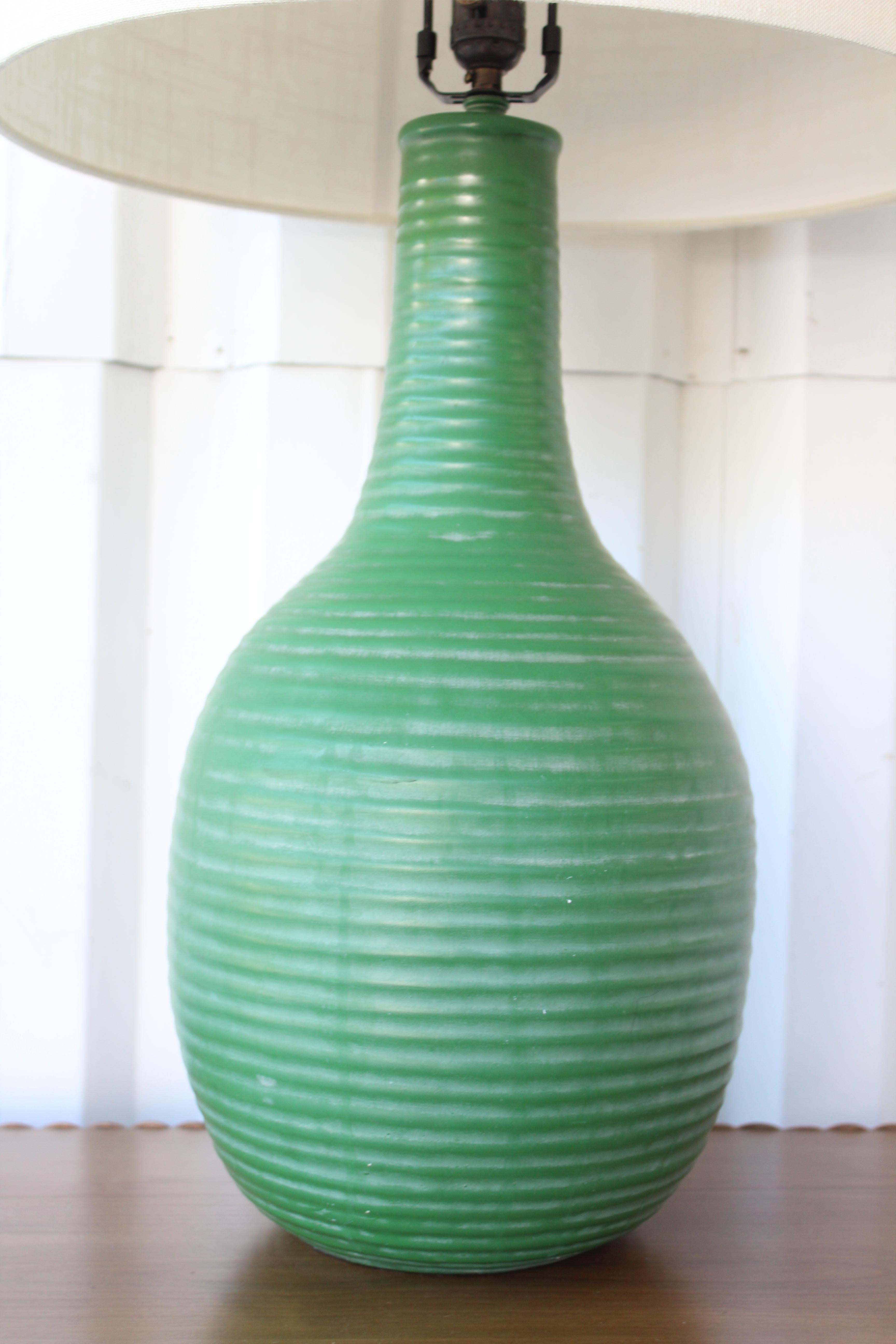 1950s ceramic lamp with ribbed texture and in a wonderful green glaze. Newly rewired and fitted with a custom shade in Belgian linen. Lamp shade is 18