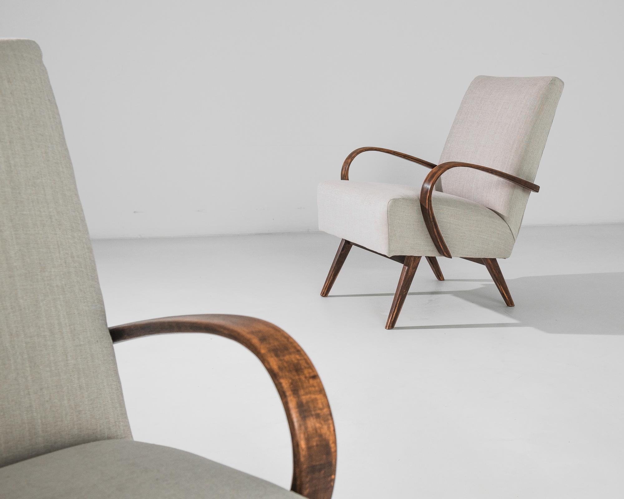 An armchair by Czech furniture designer Jindrich Halabala. This 1950s design is upholstered in an updated beige fabric, the neutral tone was chosen to compliment the natural brown of the hardwood frame. Influenced by Modern and Art Deco design, the
