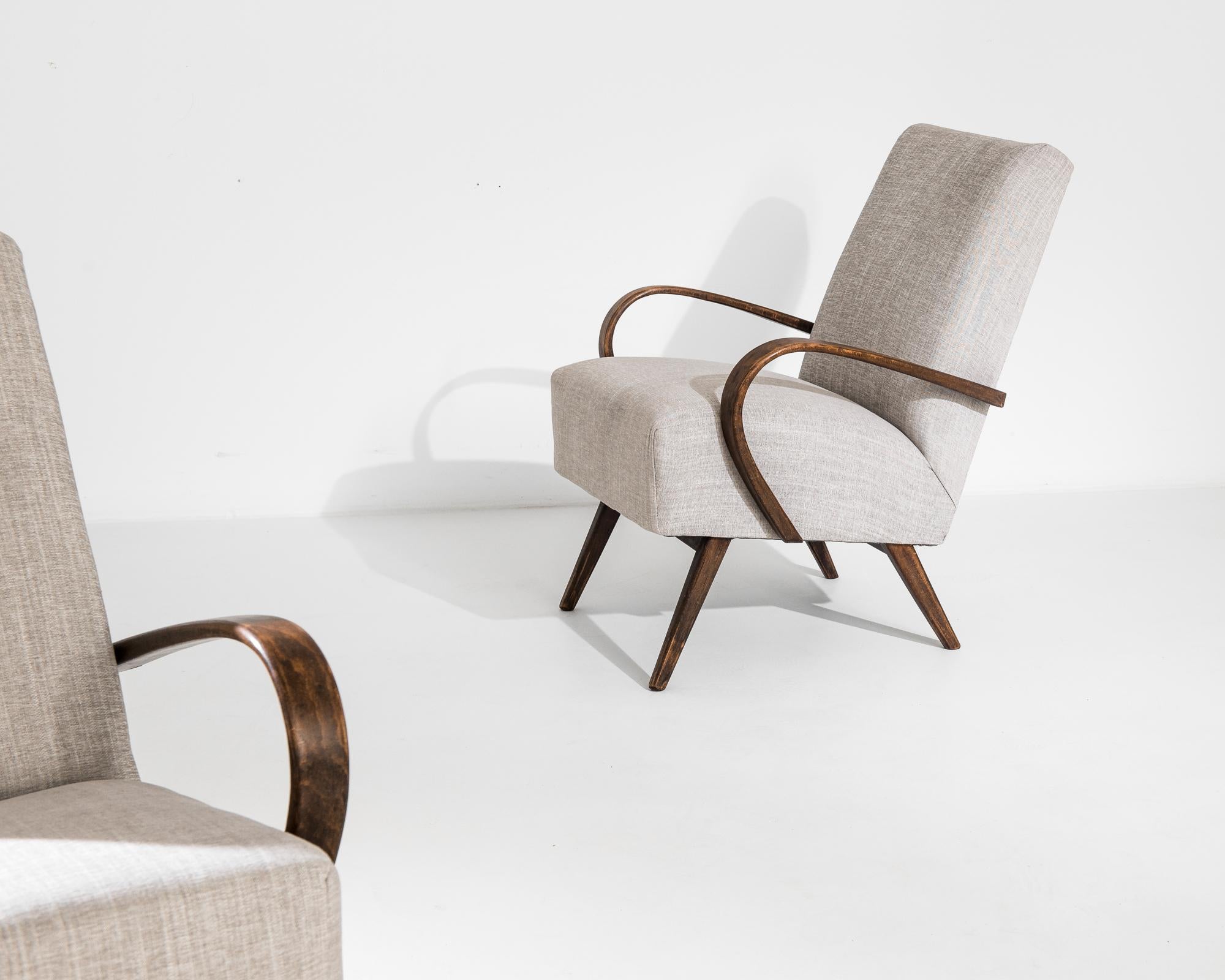 A pair of armchairs by Czech furniture designer Jindrich Halabala. This 1950s design is upholstered in an updated ecru fabric, the soothing earth tone was chosen to compliment the natural brown of the hardwood frame. Influenced by Modern and Art