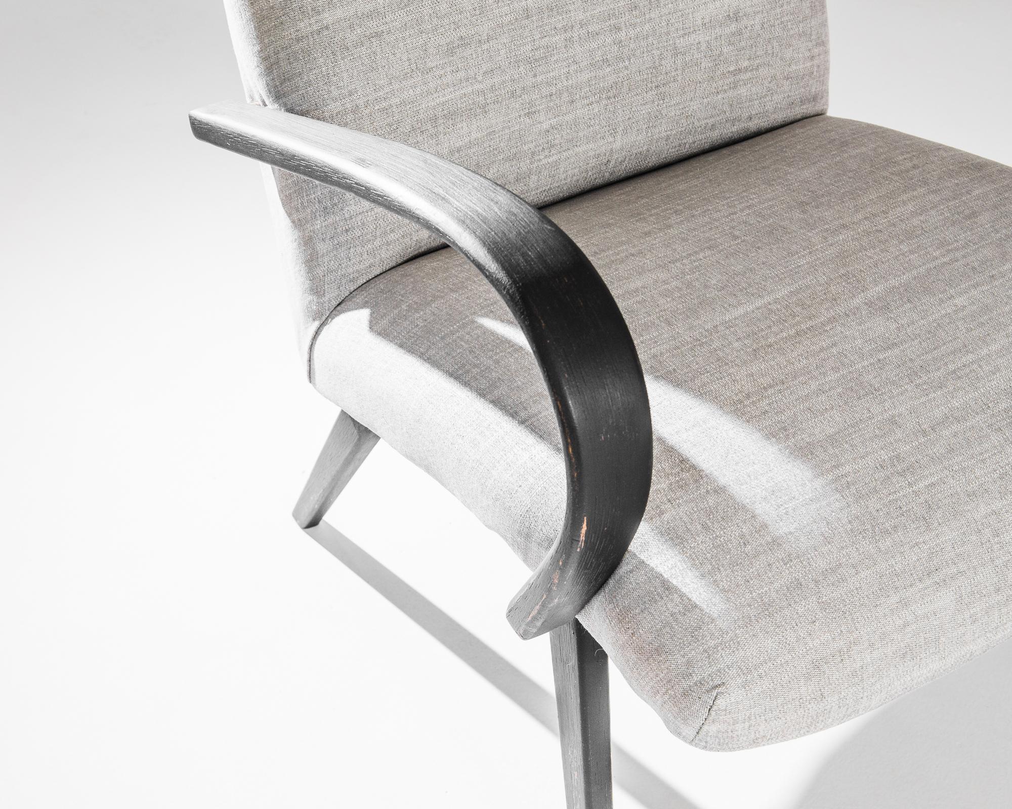 A pair of armchairs by Czech furniture designer Jindrich Halabala. This 1950s design is upholstered in an updated beige fabric, the soothing earth tone was chosen to compliment the textured black of the hardwood frame. Influenced by Modern and Art