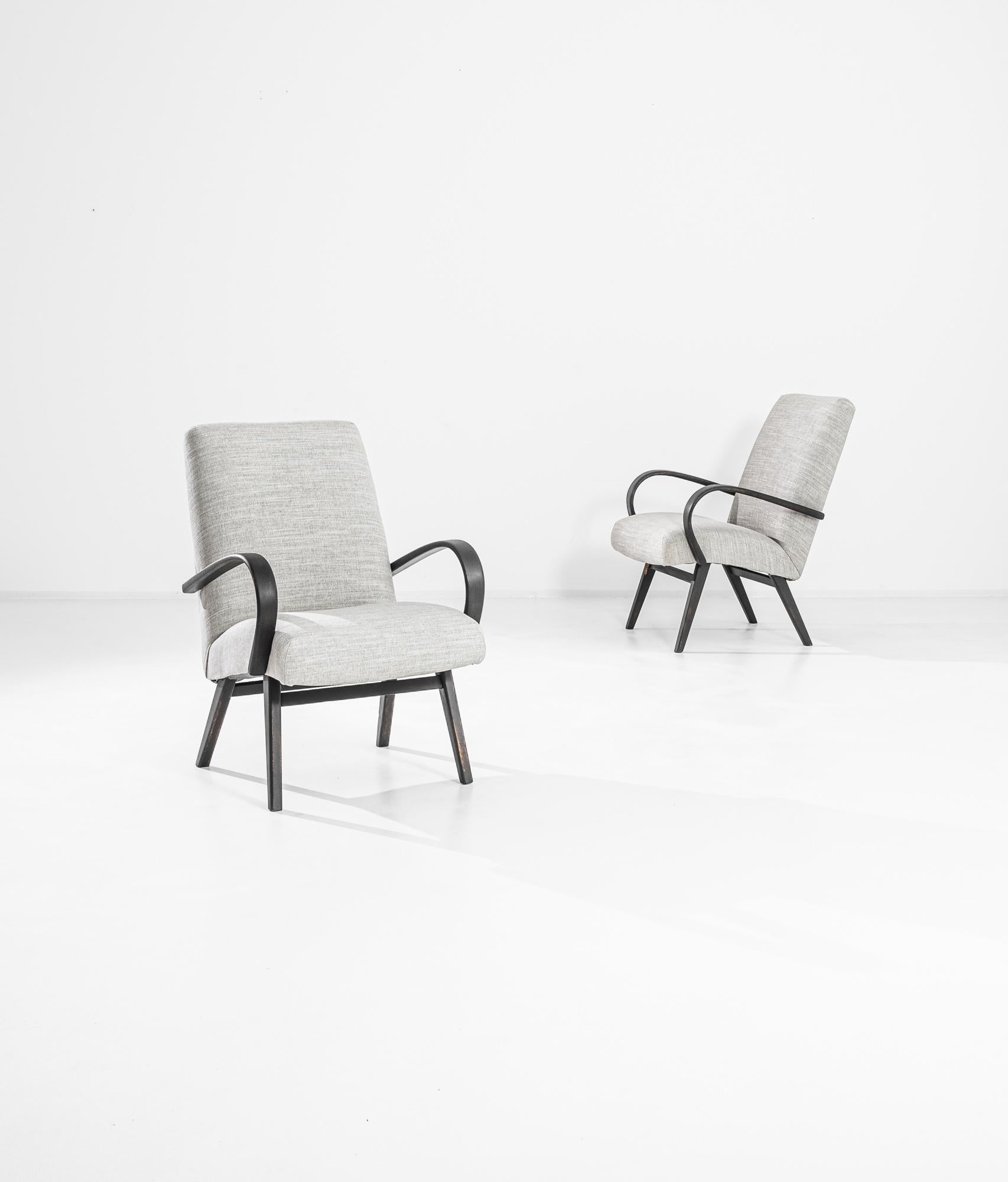 A pair of armchairs by Czech furniture designer Jindrich Halabala. This 1950s design is upholstered in an updated beige fabric, the soothing earth tone was chosen to compliment the textured black of the hardwood frame. Influenced by Modern and Art