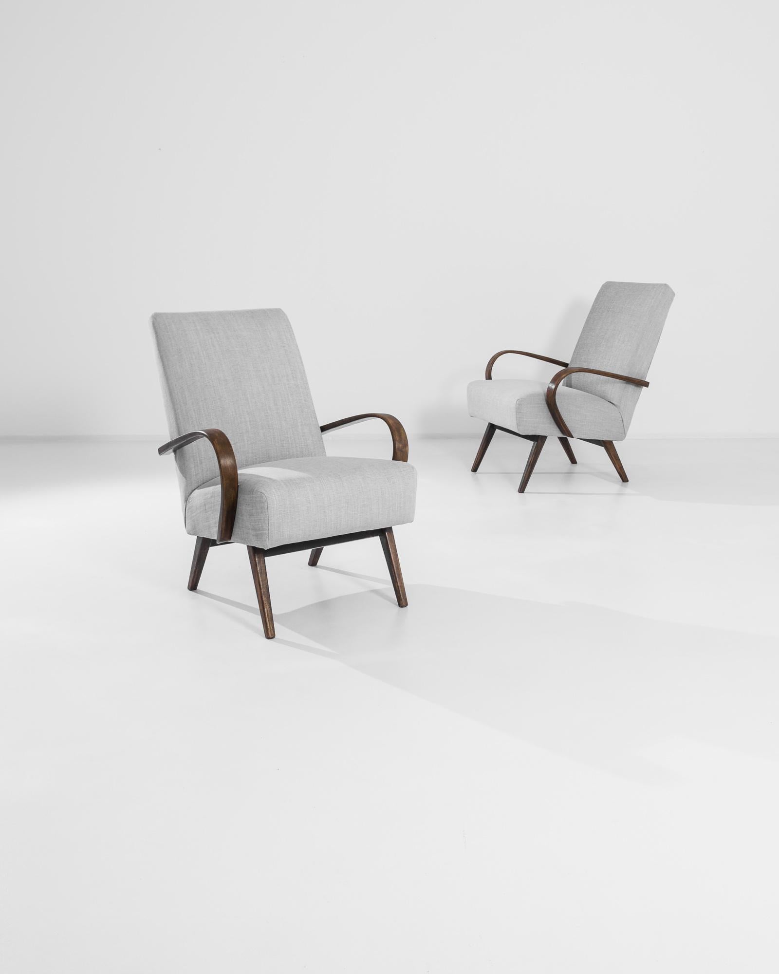 A pair of armchairs by Czech furniture designer Jindrich Halabala. This 1950s design is upholstered in an updated gray fabric, the soothing heather tone was chosen to compliment the dark stain of the hardwood frame. Influenced by Modern and Art Deco