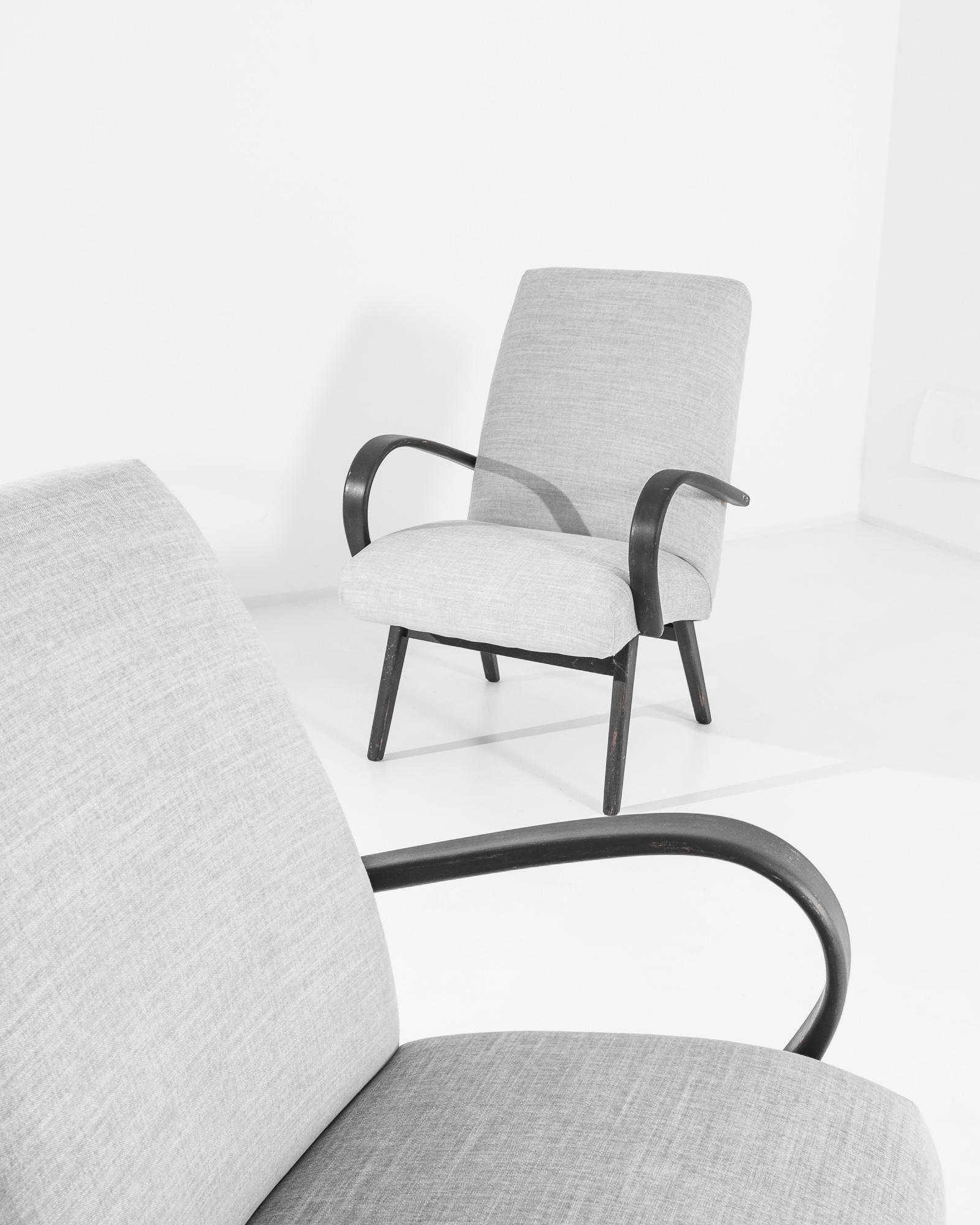 Une paire de fauteuils du designer de meubles tchèque Jindrich Halabala. Ce modèle des années 1950 est tapissé d'un tissu gris actualisé. Le ton apaisant de la bruyère a été choisi pour compléter le noir rêche de la structure en bois dur.