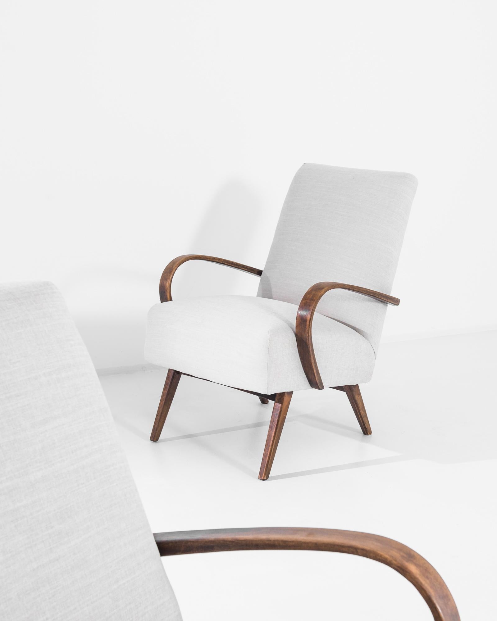 A pair of armchairs by Czech furniture designer Jindrich Halabala. This 1950s design is upholstered in an updated gray fabric, the soothing heather tone was chosen to compliment the dark stain of the hardwood frame. Influenced by Modern and Art Deco