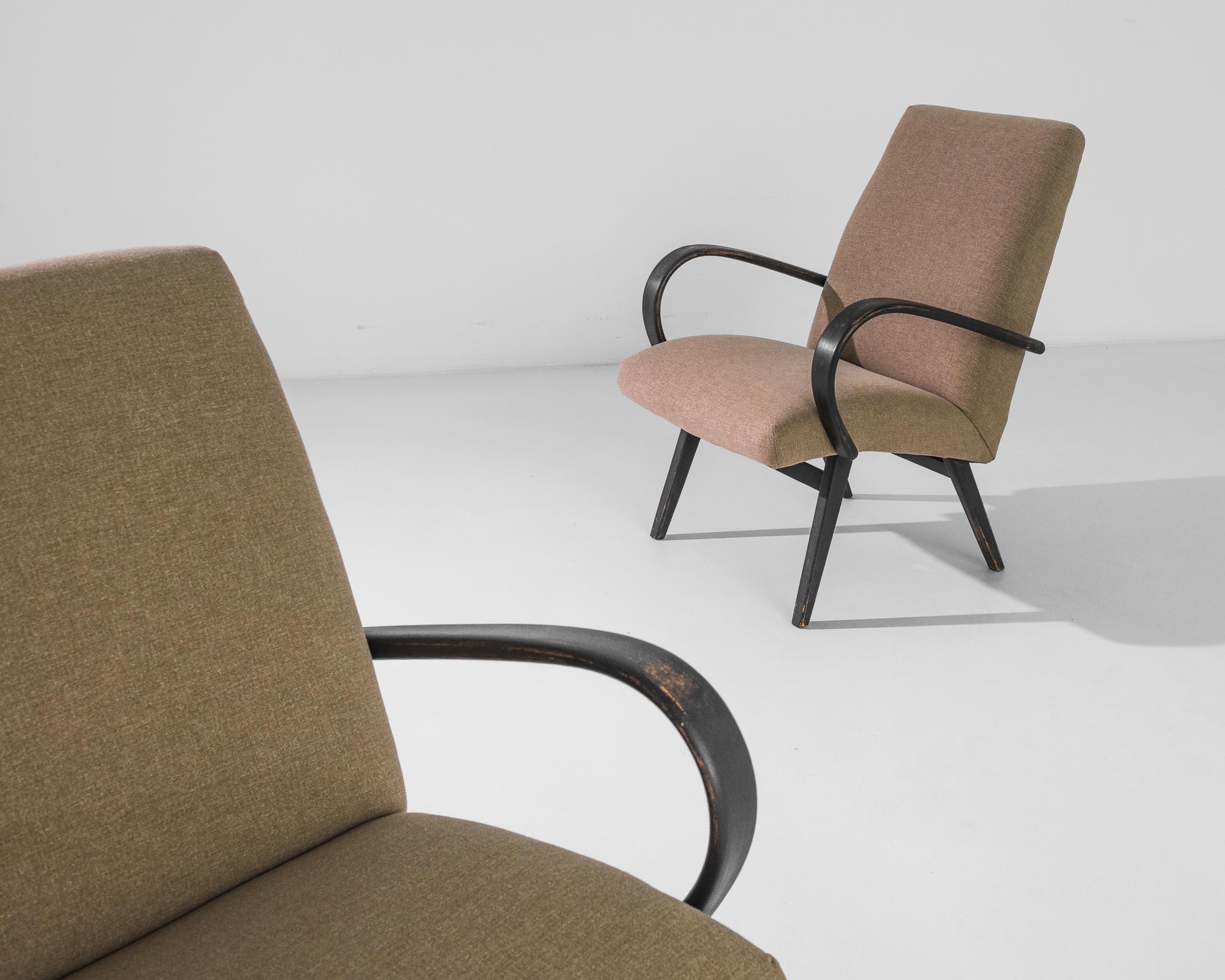 A pair of armchairs by Czech furniture designer Jindrich Halabala. This 1950s design is upholstered in an updated brown fabric, the soothing earth tone was chosen to compliment the textured black of the hardwood frame. Influenced by Modern and Art