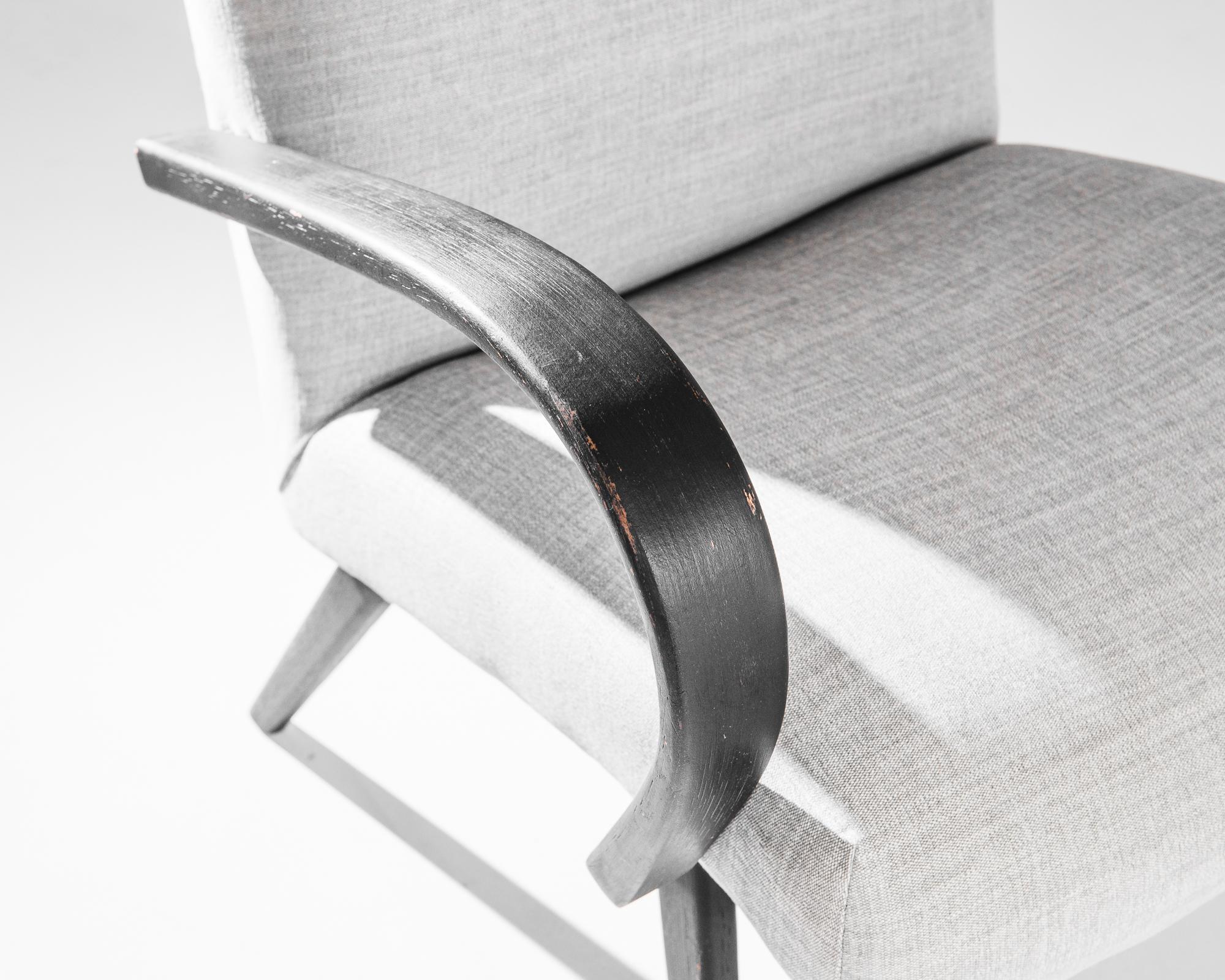 A pair of armchairs by Czech furniture designer Jindrich Halabala. This 1950s design is upholstered in an updated grey fabric, the soothing tone was chosen to compliment the textured black of the hardwood frame. Influenced by Modern and Art Deco
