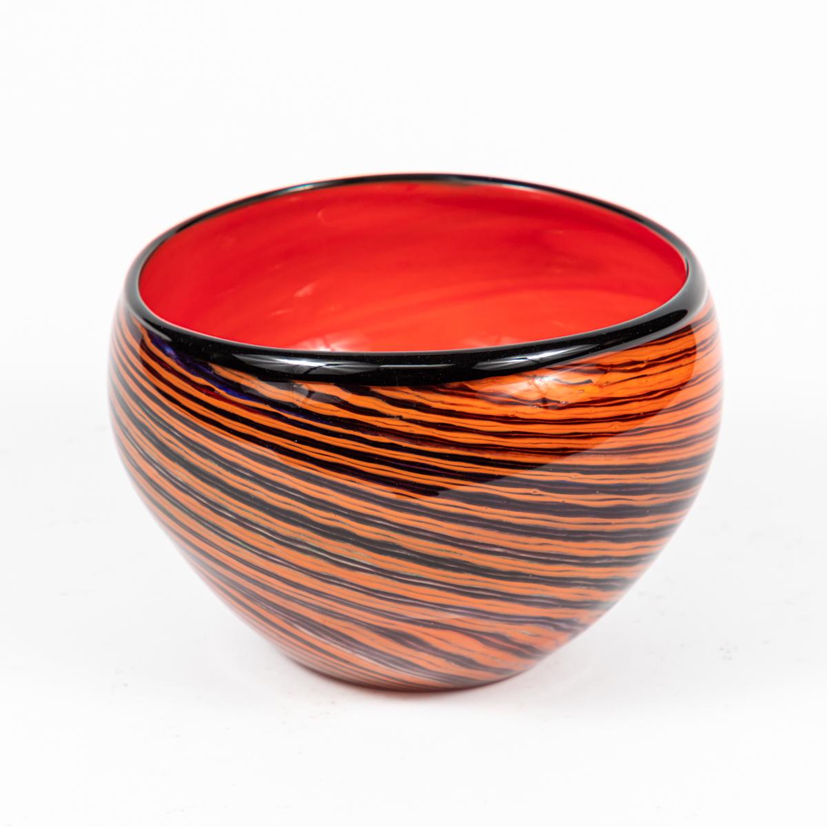 1950s English red and orange studio glass bowl wrapped in thin swirls of purple and black hand-painted stripes. Swank and psychedelic, this midcentury vessel is evocative of Murano glass. The multi-dimensional pattern is hypnotizing, the glossy