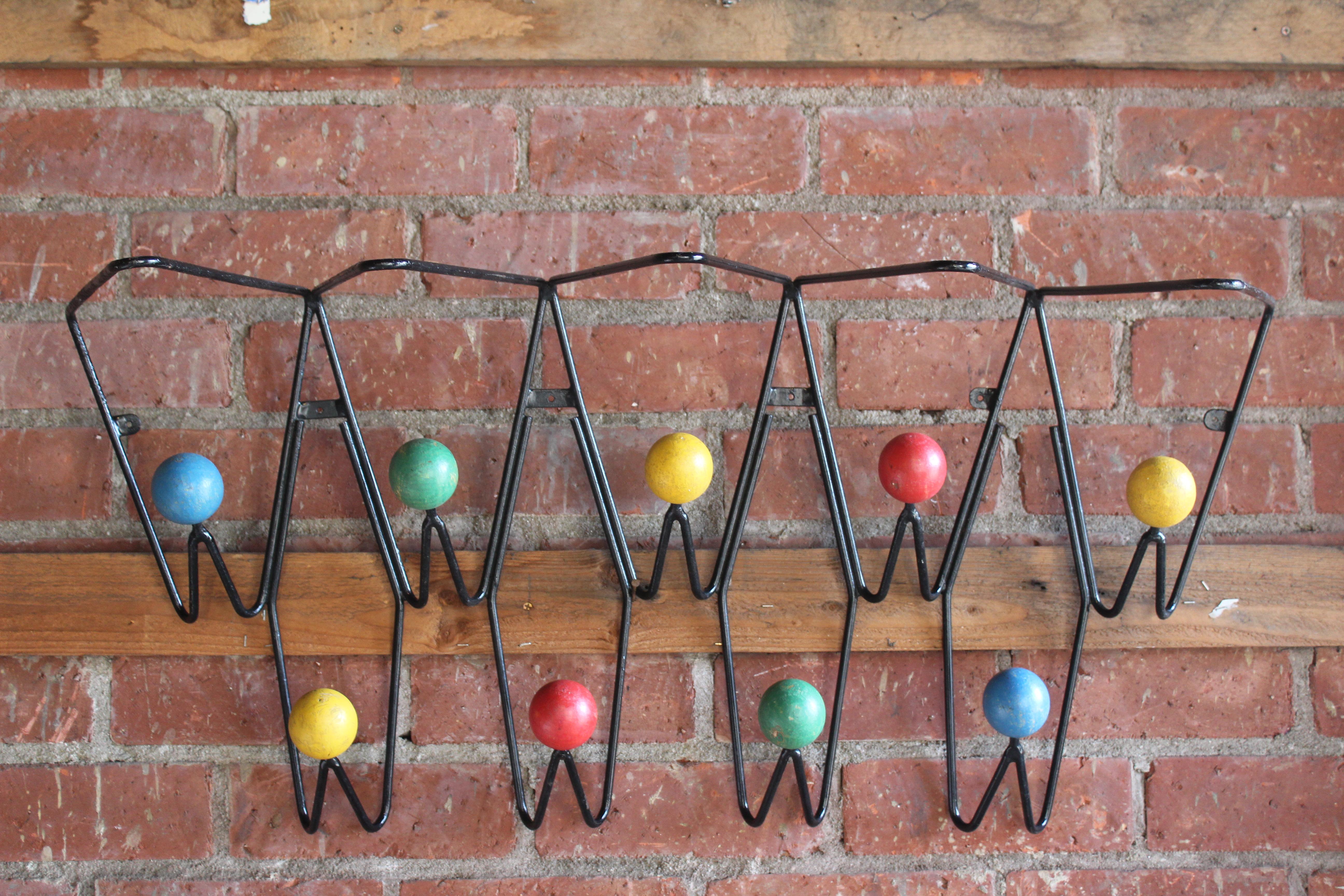A vintage French coat rack designed by Roger Feraud, 1950s. Made of iron with painted wood balls to hang your coats and hats. The top can be used as a shelf for hats as well. In overall wonderful condition with patina to the painted balls. 41
