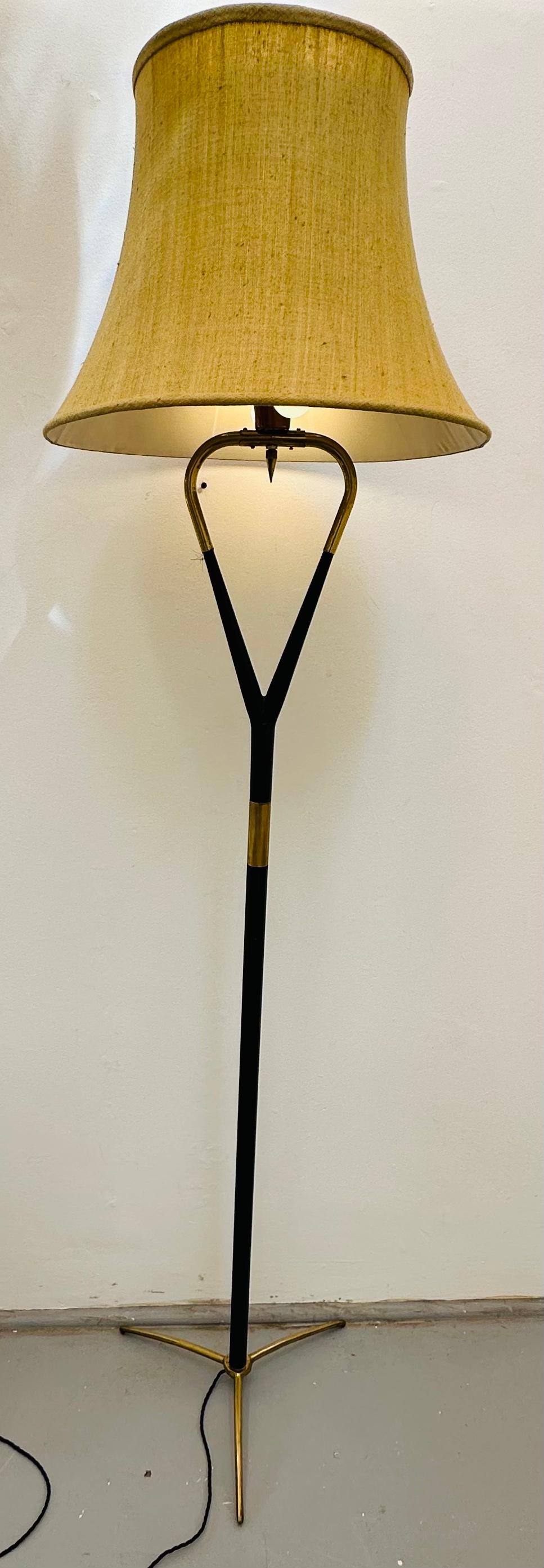 A stunning 1950s mid century brass and black lacquered gloss wood tripod floor lamp.  The floor lamp stands on a brass tripod base with a feature detail ribbed brass band situated on the lacquered supporting stem towards the heart-shaped