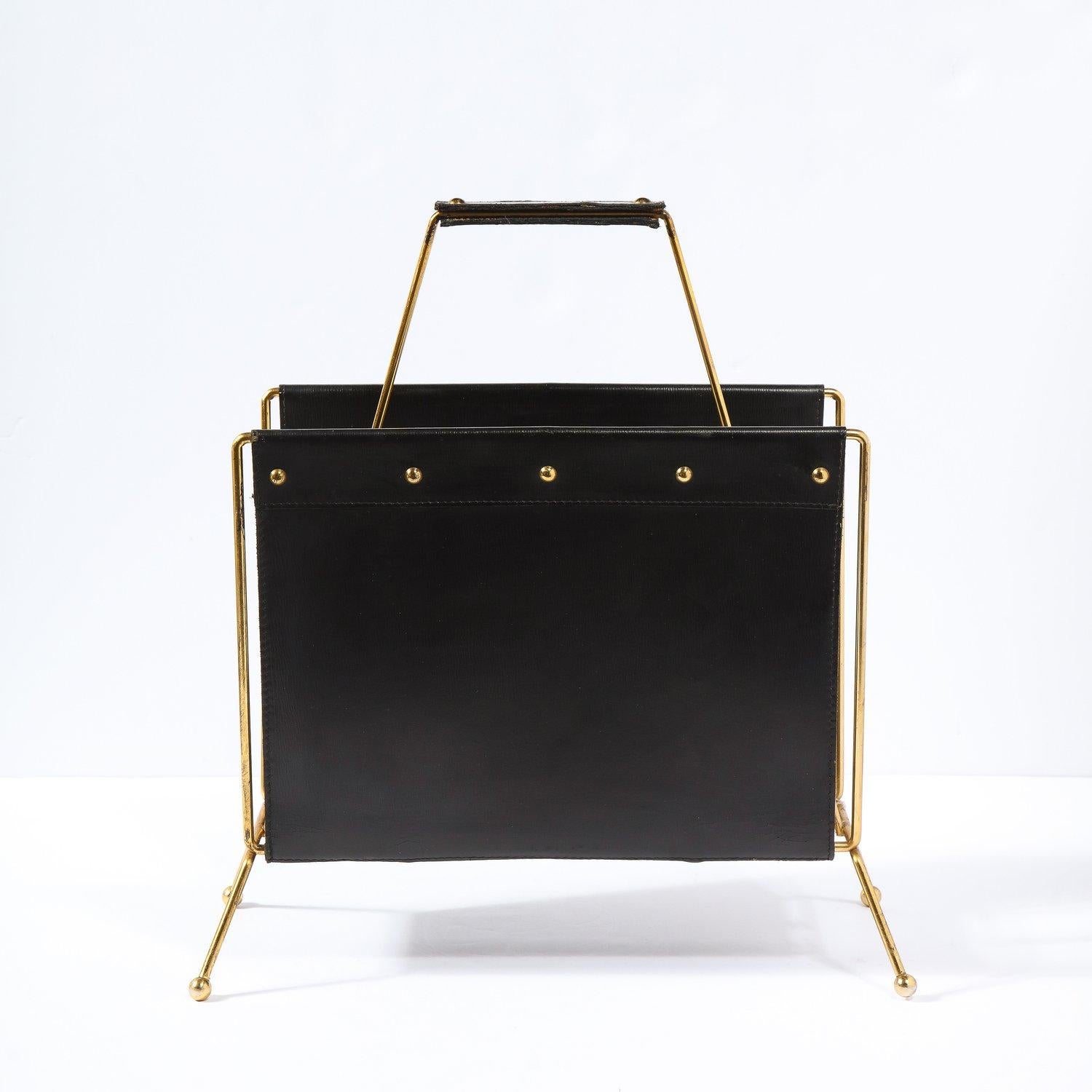 This classic leather and brass magazine stand was realized in in the manner of Jacques Adnet. The French art deco modernist designer, architect and interior designer was renowned for his furniture and accessory designs in leather. His work is highly