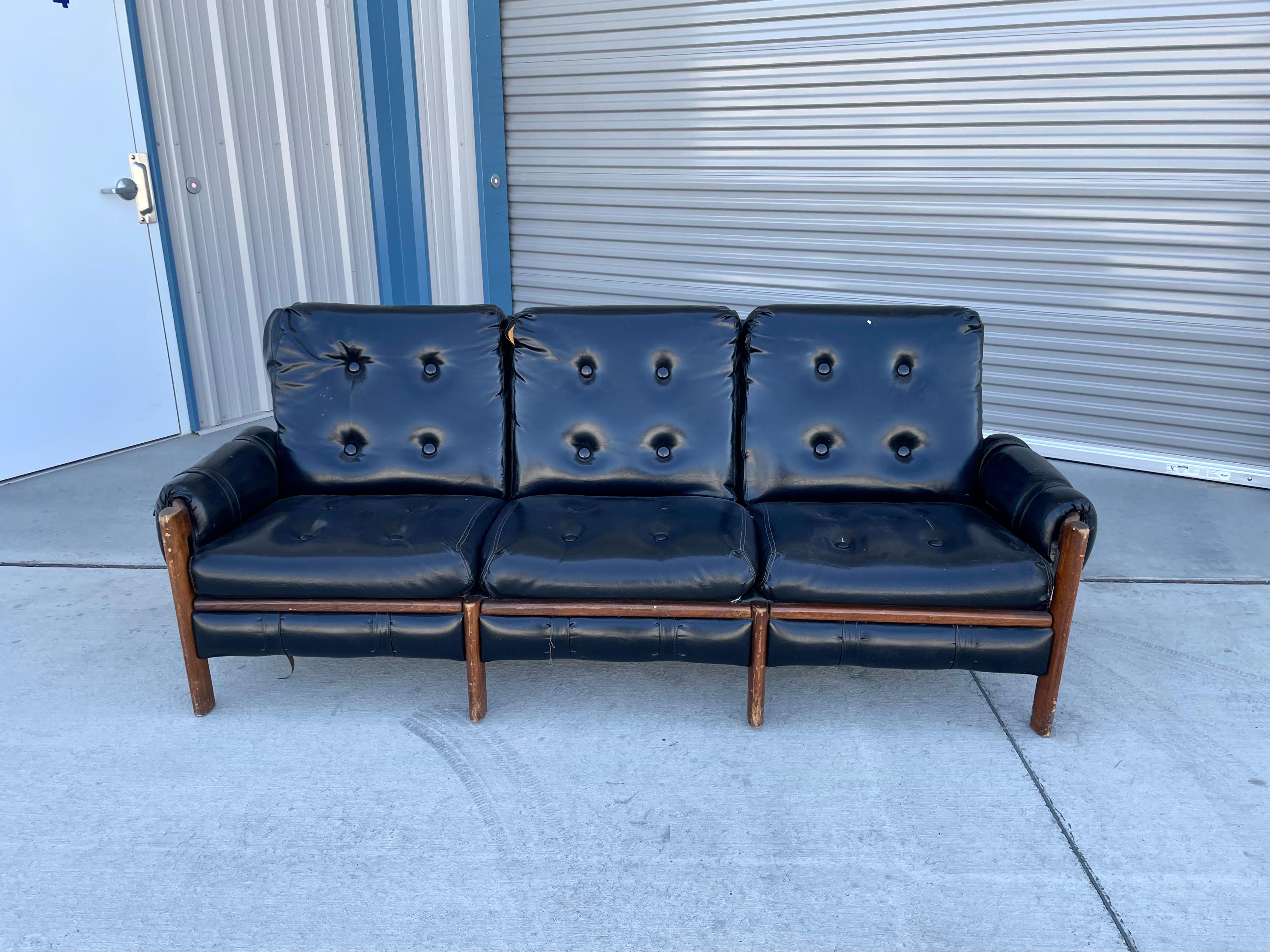 Mid-century leather safari sofa designed and manufactured in the United States 1950s. This stunning sofa features a black leather upholstery that sits on a walnut frame guaranteed to draw attention in any room and is just amazing to relax in.