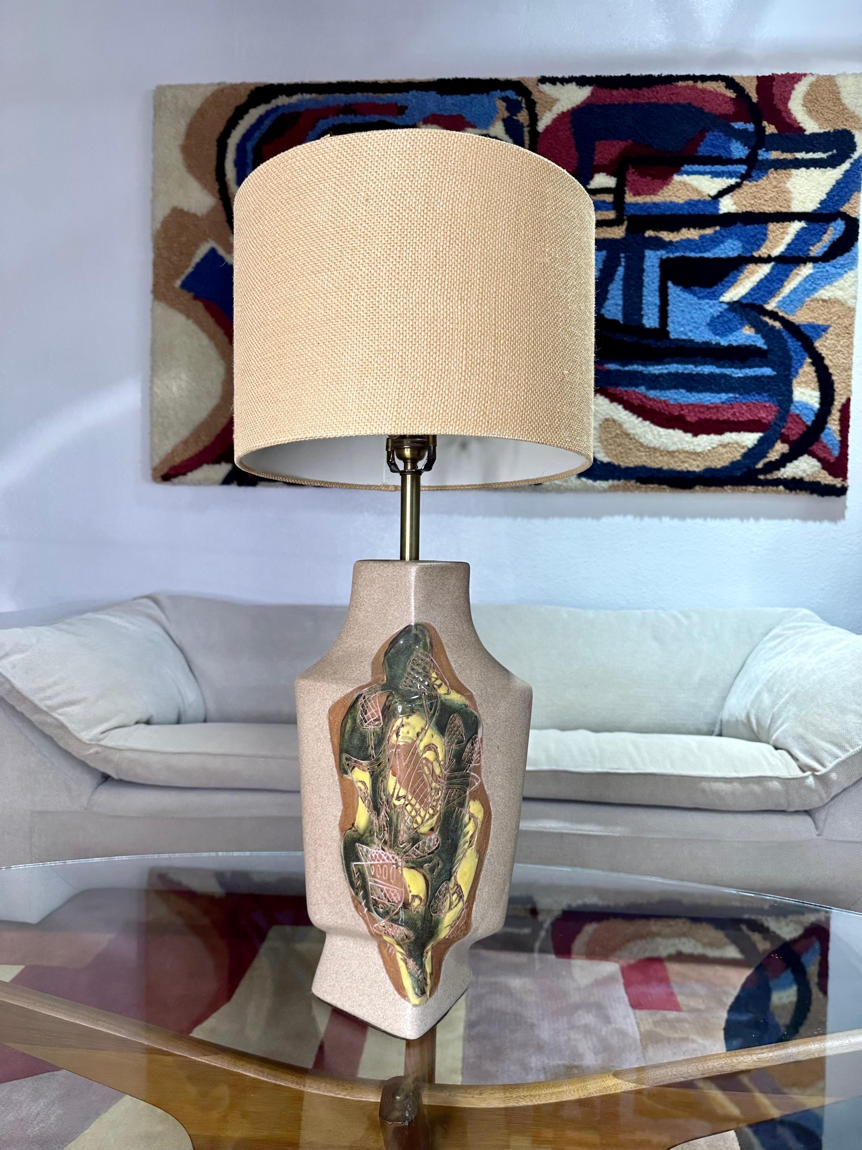 Precioso ejemplo de la iluminación de Marianna von Allesch, esta lámpara de sobremesa de cerámica de principios de los años 50, con cuerpo de color arenisca claro, tiene grabados con esmalte verde, topo y amarillo en dos esquinas. Se ve muy bien