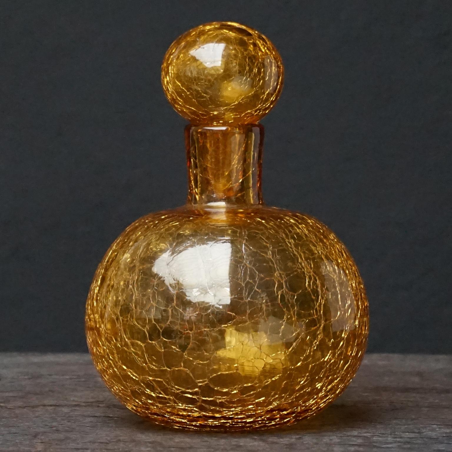 Hübsche kleine bernsteingelbe Blenko-Karaffe aus den 1950er Jahren aus mundgeblasenem Craquelé-Kunstglas mit Stopfen und sichtbarem Pontil.
Blenko Glass Company ist ein amerikanisches Familienunternehmen, das seit 1893 besteht. 
Seit 1921 haben
