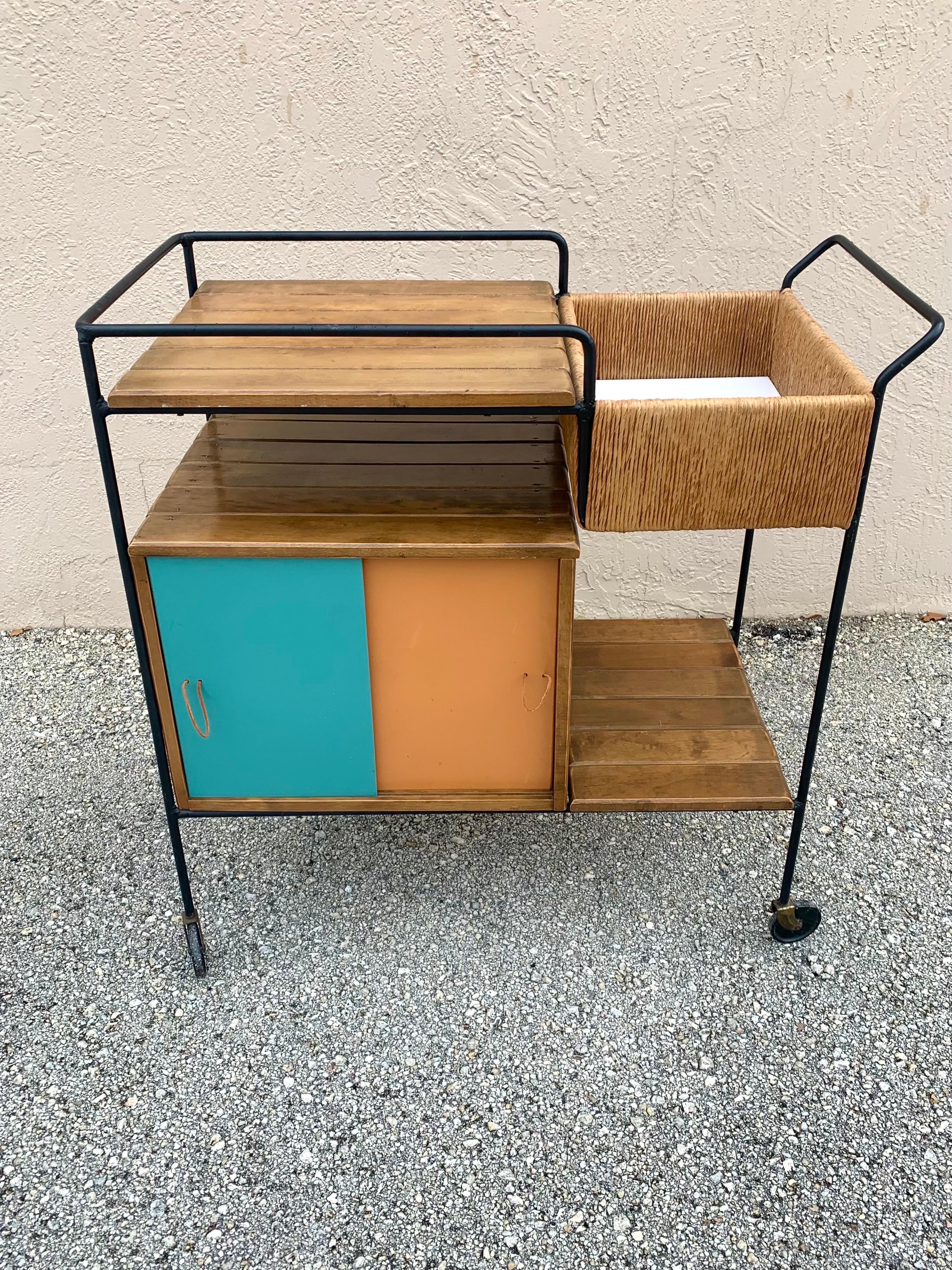 Mid-Century Modern Bar Cart designed by Arthur Umanoff. Aged iron frame with rush trim and slatted wood. Reversible Masonite sliding drawers appear on both sides. Both sides are able to be presented. The Masonite drawers are all white on one side.