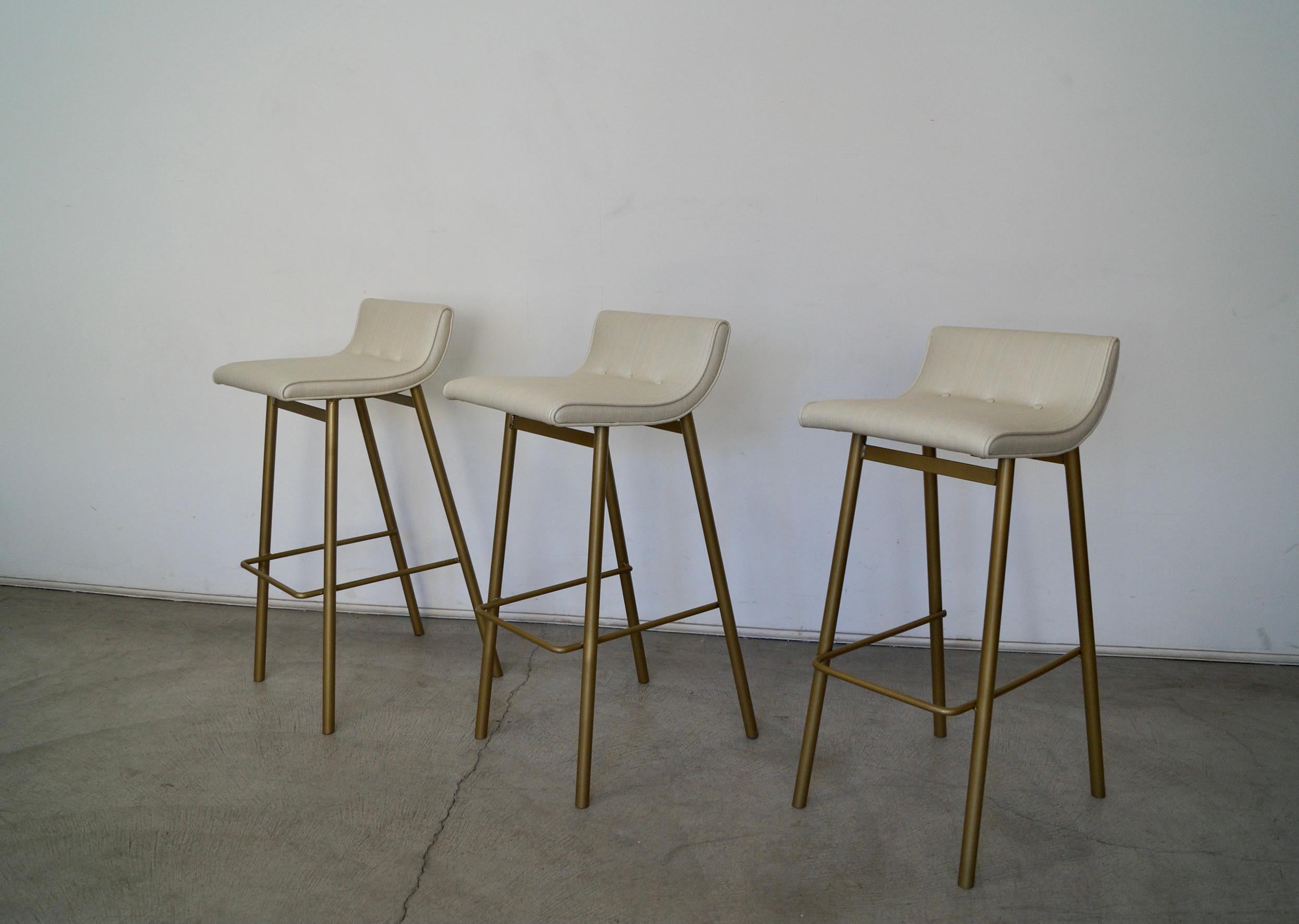 Vintage 1950's Mid-century Modern barstools for sale. The metal bases were previously professionally sandblasted and powder coated in a metallic gold brass, and have been reupholstered in a vinyl by Knoll. They were manufactured by Vista of