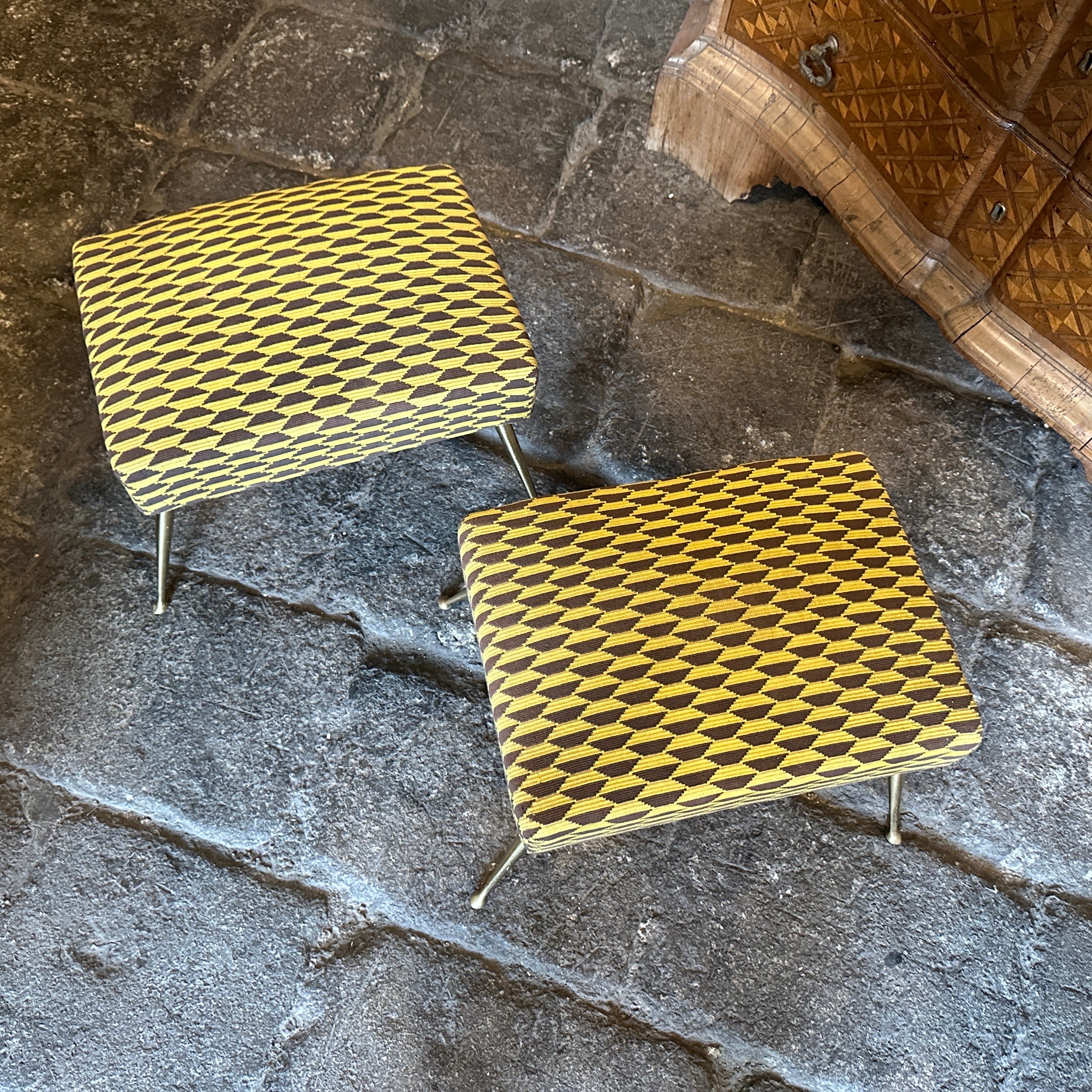A pair of stools in brass and yellow and brown Dedar fabric, designed and manufactured in Italy in the Fifties, are in original patina and condition. These stools are both functional and stylish additions to any interior space, embodying the