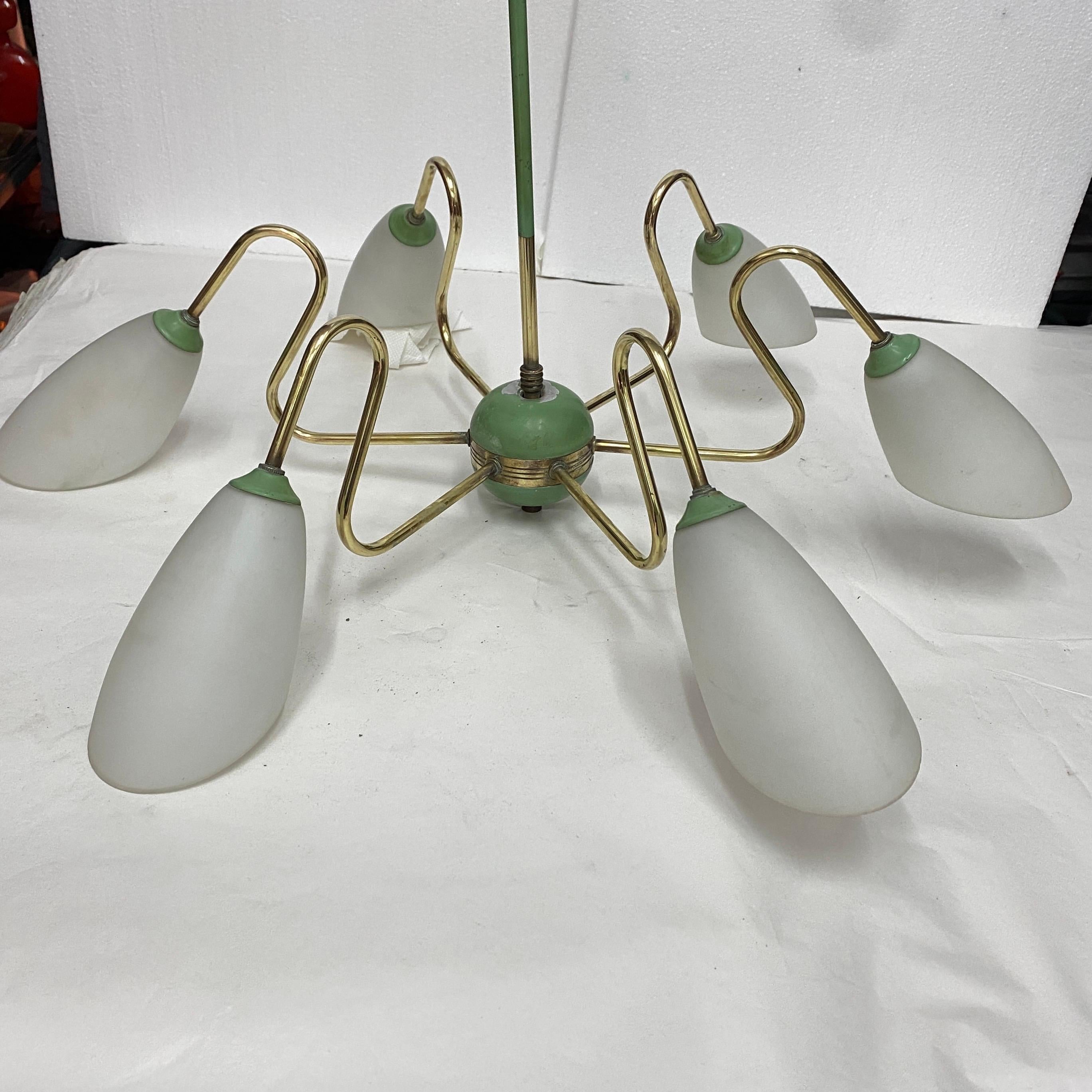 A brass and glass spider chandelier designed and manufactured in Italy in the Fifties in the manner of Stilnovo, brass has been cleaned, green painted metal it's in original conditions. it works both 110-240 volts and needs regular e 14 bulbs.