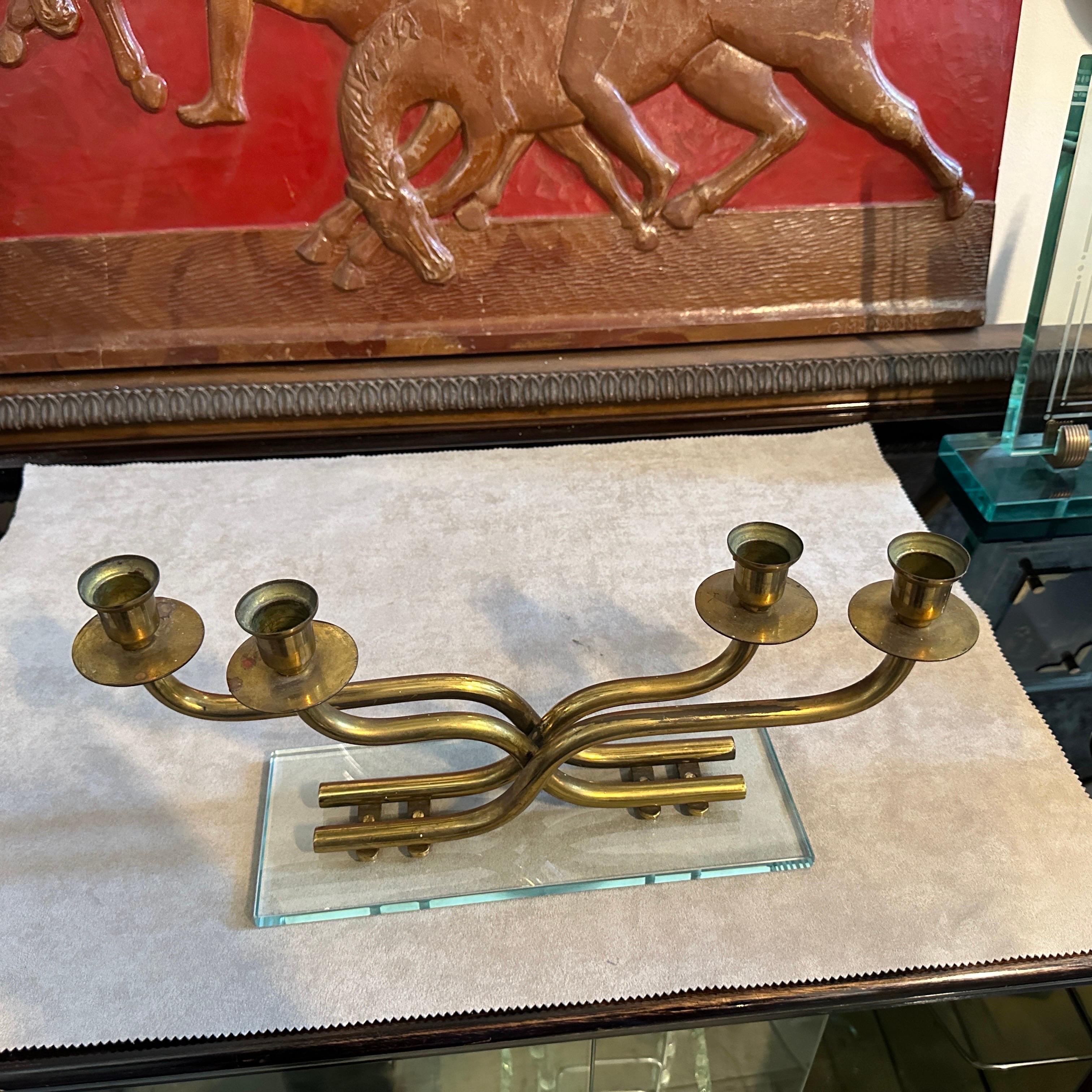 A mid-century Modern candelabra designed and manufactured in Italy in the manner of Fontana Arte, brass it's in original patina, glass it's in perfect condition. This Italian candelabra serves as a captivating centerpiece, casting a warm, inviting