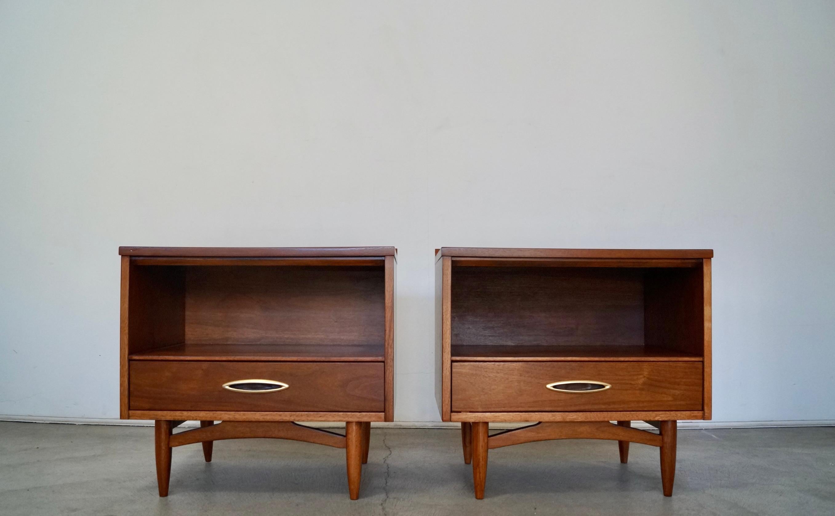 Vintage 1950's Mid-Century Modern night stands for sale. Manufactured by Broyhill, and part of the Sculptra series. They have been professionally refinished, and are made of walnut. They have the original recessed handles in a brass finish. They are