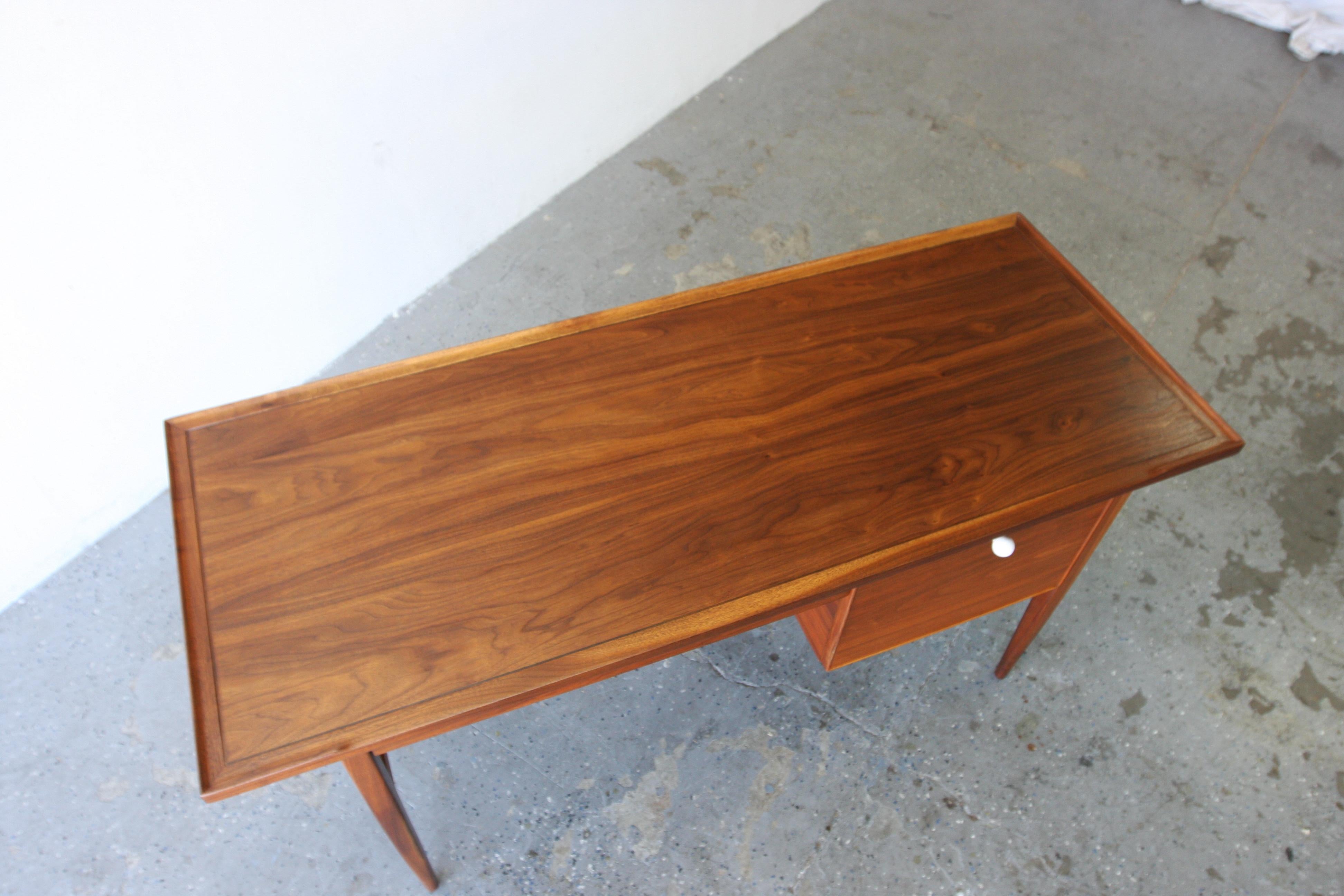 Look at this beautiful wood grained Mid century modern writing desk designed by Kipp Stewart for Drexel. Beautiful walnut grain with 2 drawers. Simple lines, sculpted legs, curved edge and finished back.

Professionally refinished, and restored

60