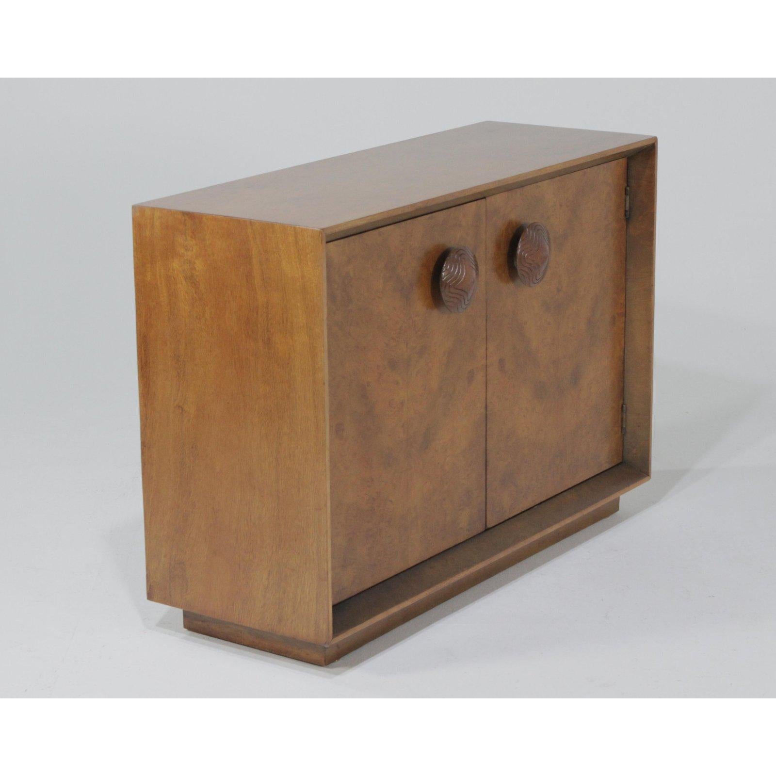 A lovely Paldao cabinet designed by Gilbert Rohde for Herman Miller. An iconic design, with wonderfully figured burl front, oversized pulls, and large recess. Mid-Century Modern meets Art Deco here, and this piece will complement many designs.