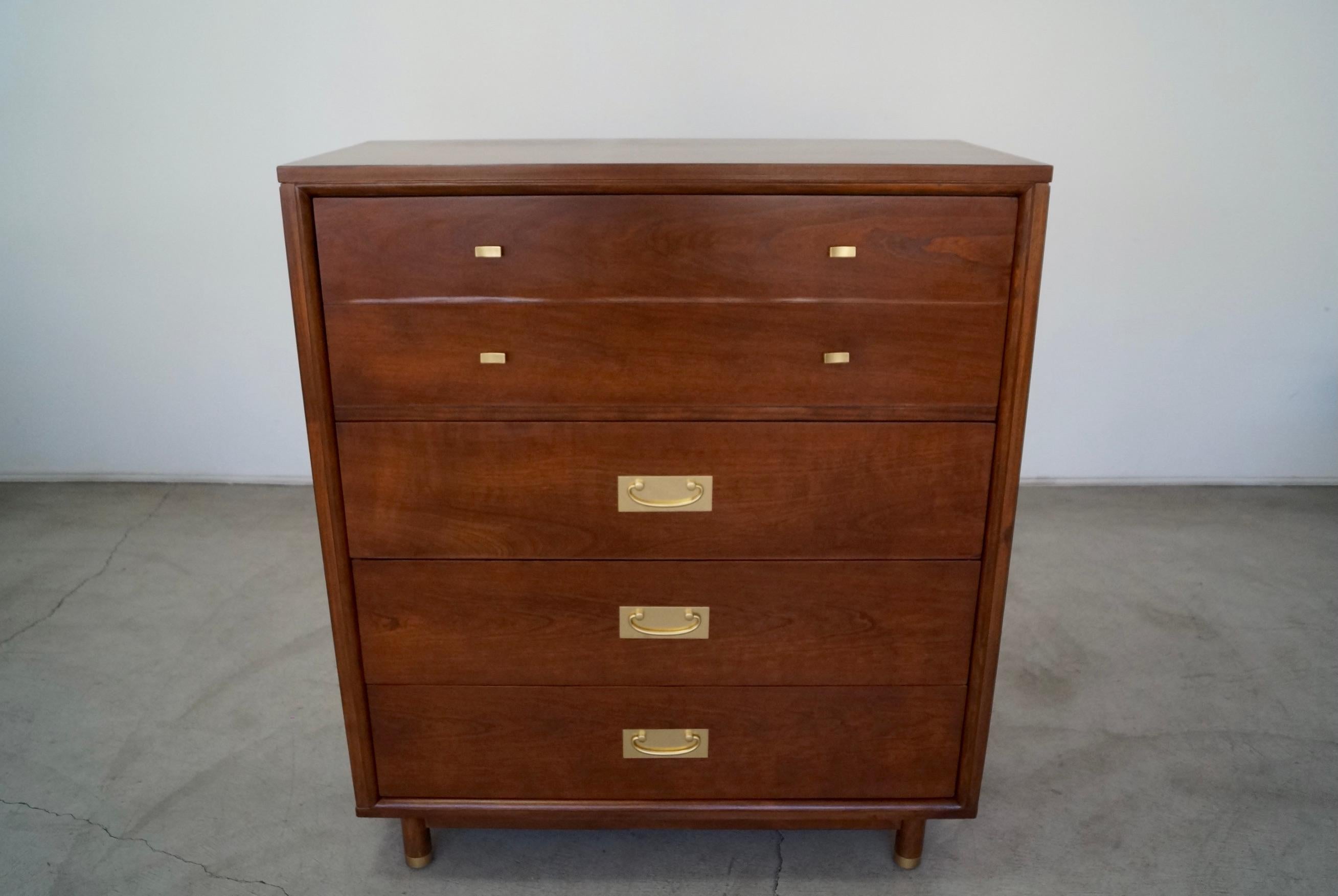 Vintage Mid-Century Modern dresser for sale. Manufactured in the 1950's, and has been professionally refinished in walnut. It's made of cherry, and has the original solid brass pull handles. It has cylinder legs capped in solid brass. This dresser
