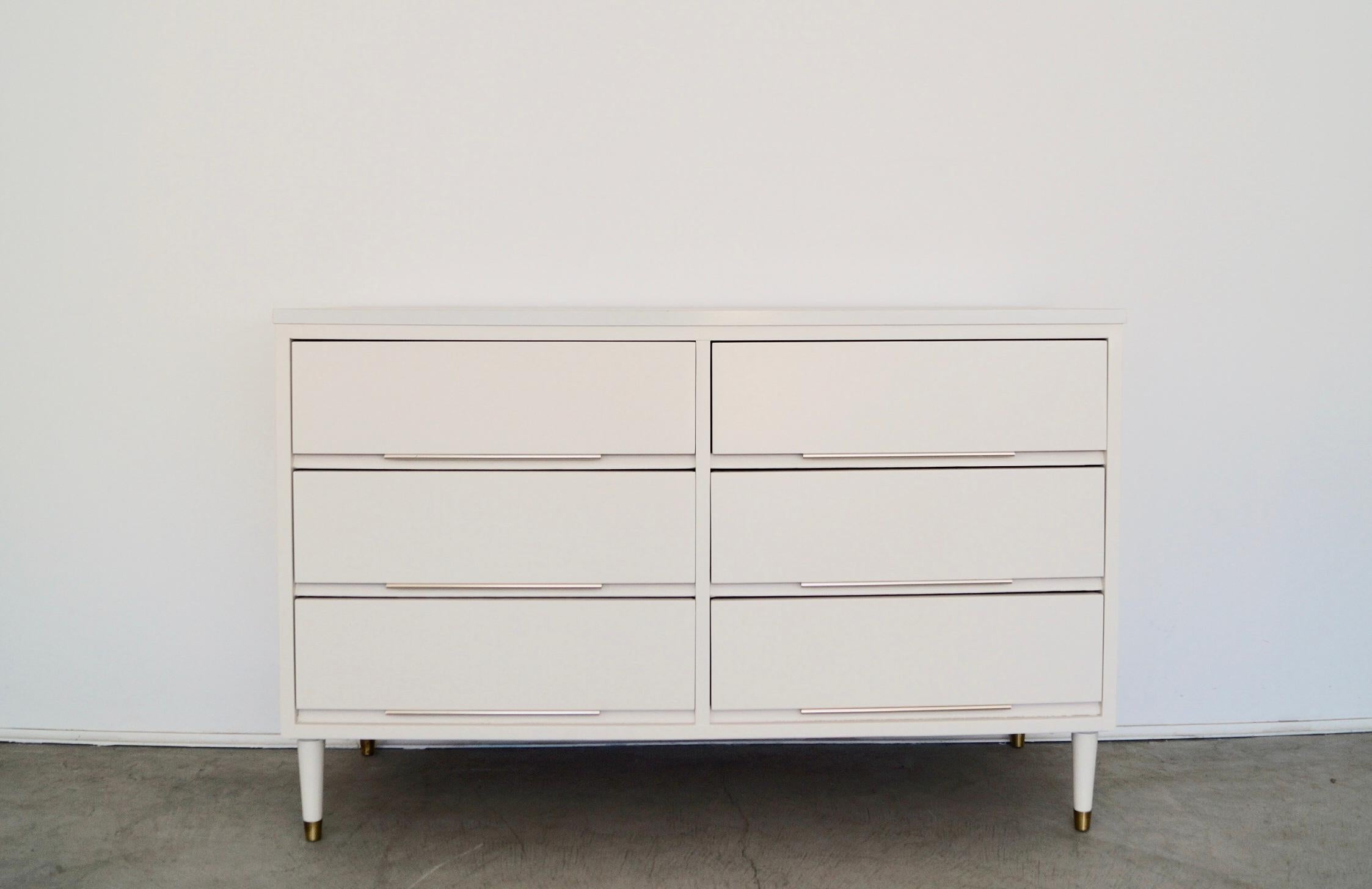 We have this lovely original Mid-century Modern dresser for sale. It was professionally refinished in white, and has the original aluminum pull handles in brass. It has the classic tapered pencil legs capped in brass, and is a high-quality piece