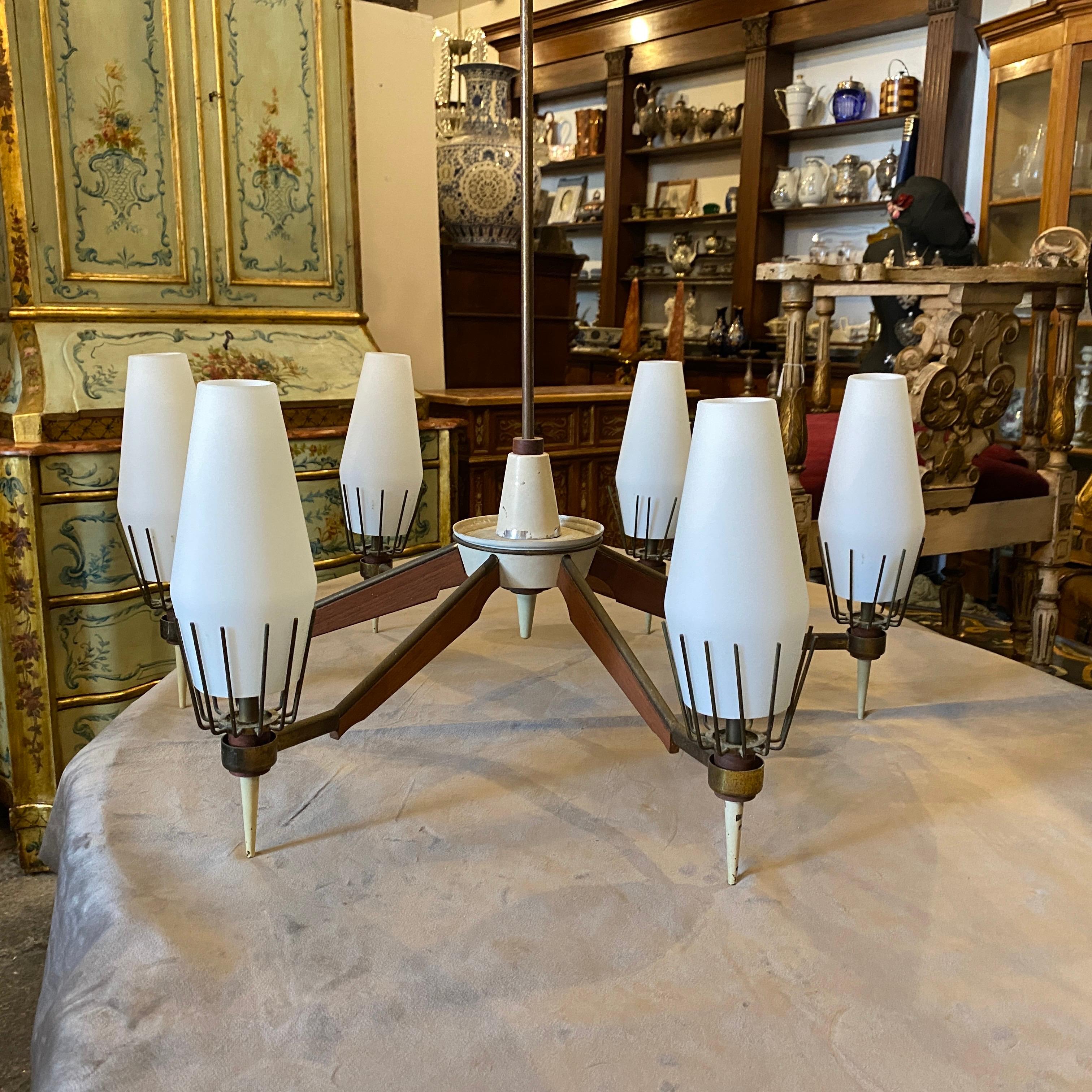 A brass, teak and glass chandelier made in Italy in the Fifties. It's in original conditions, the white opaline glasses are in perfect condition, it works 110-240 volts and needs 6 regular e14 bulbs. This chandelier exemplifies the elegant and