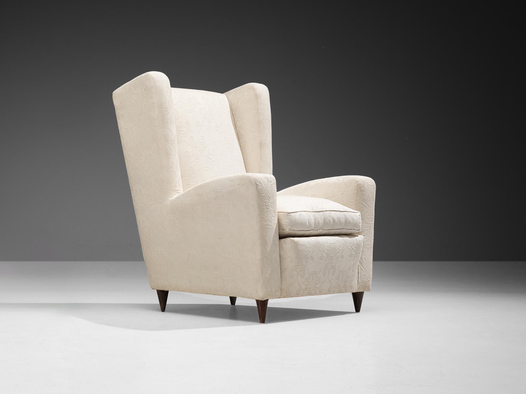 Easy chair, fabric, wood, Italy, 1950s.

This Classic Italian Postwar wingback chair has an unusually high back and gracious wings that contain dramatized pointed corners. The armrests feature the same pronounced curves that give the utmost comfort